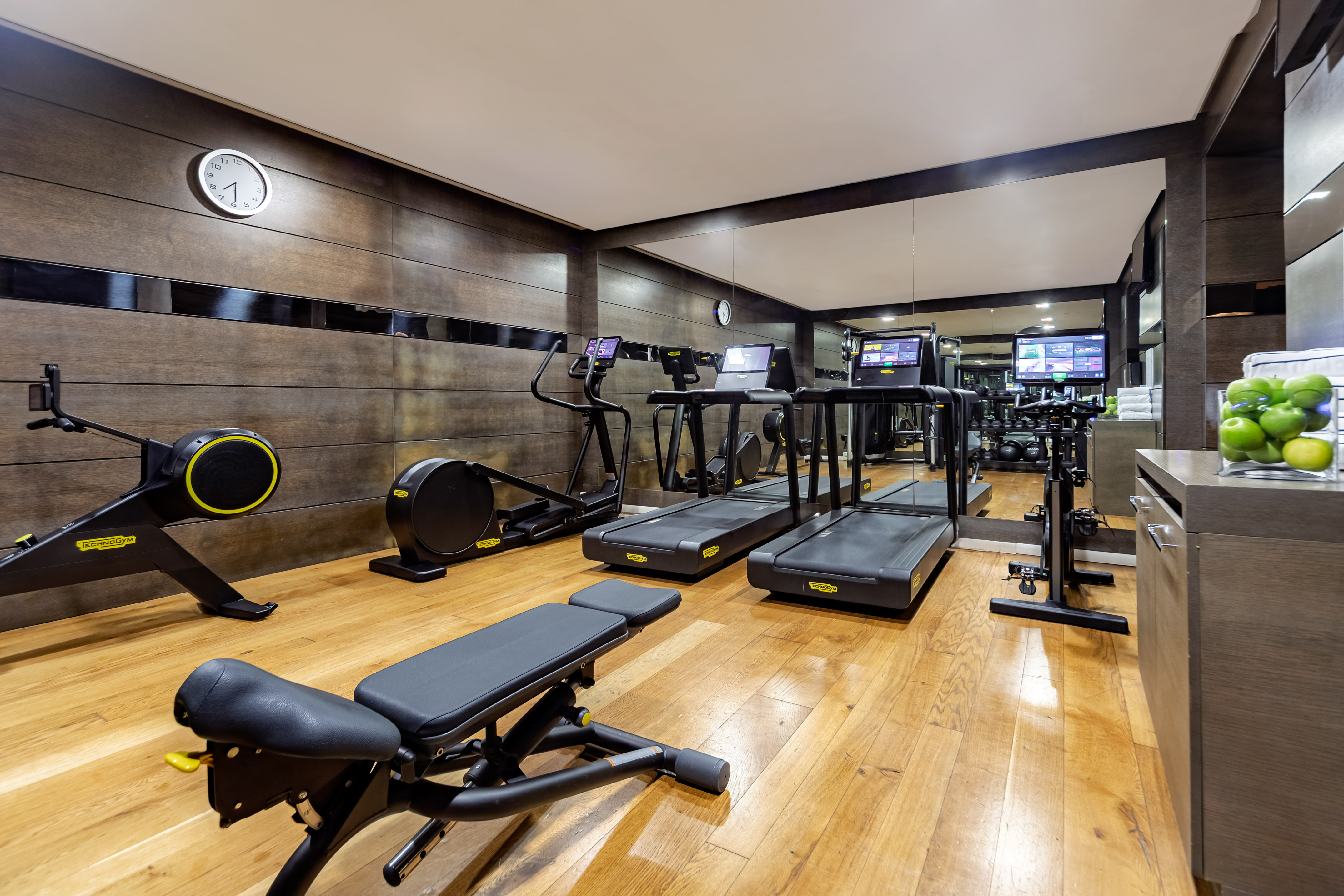 Modern gym with treadmills, rower, elliptical, and weight bench.