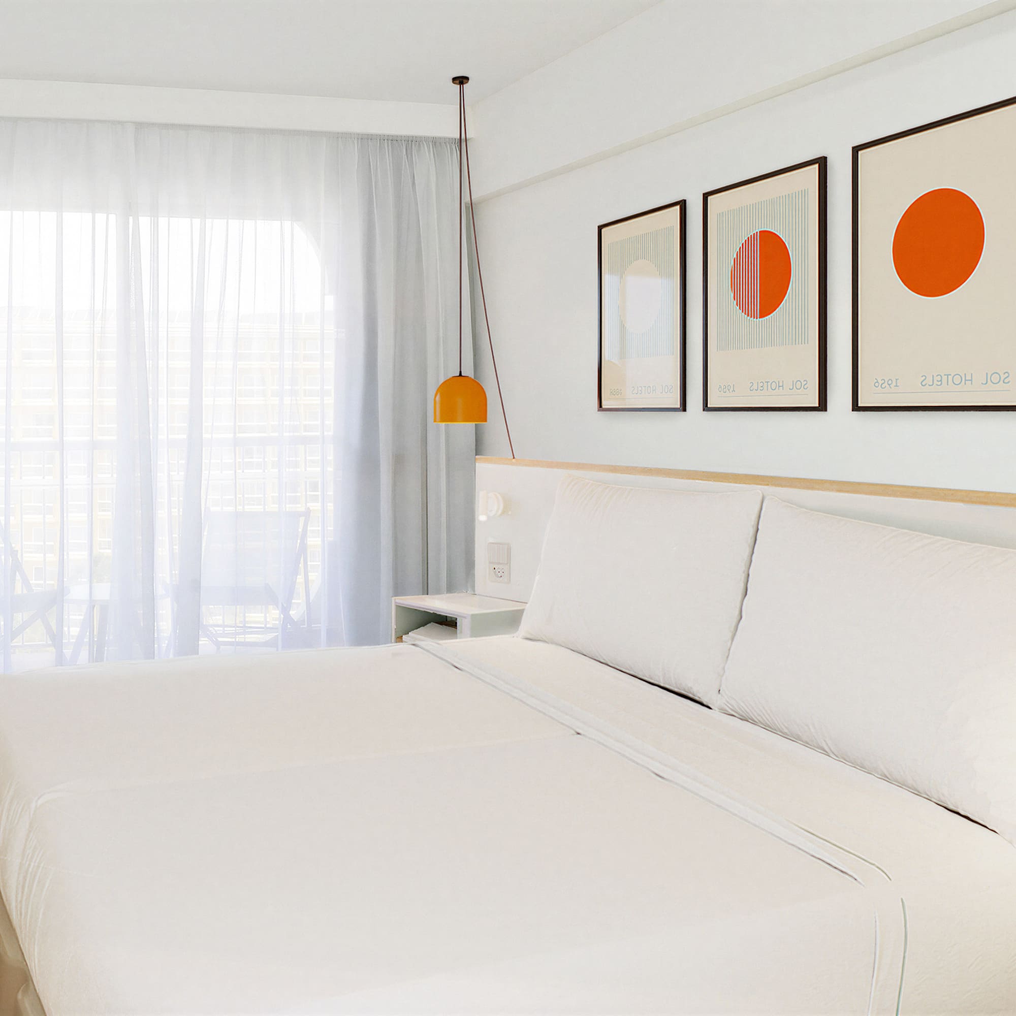 a bed with white sheets and orange art on the wall