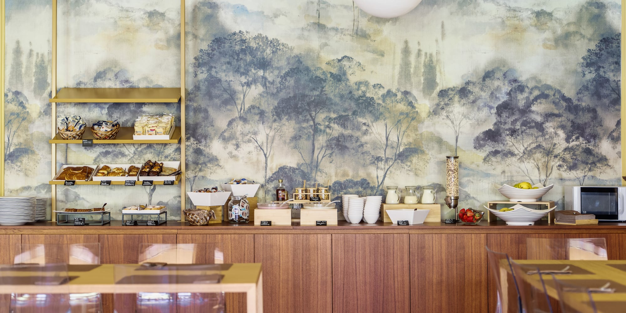 Bright hotel breakfast buffet with diverse foods and scenic mural.