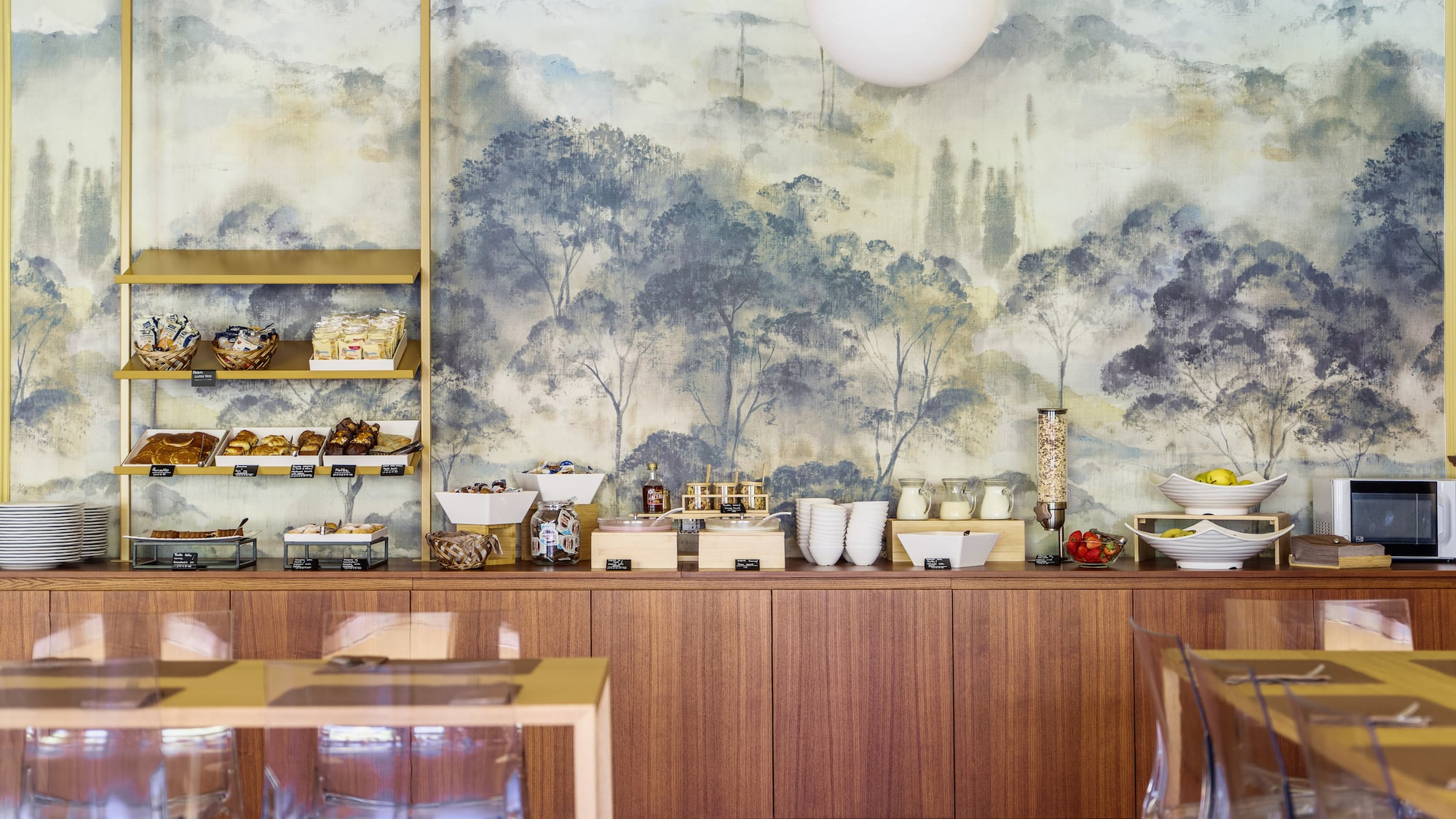 Bright hotel breakfast buffet with diverse foods and scenic mural.