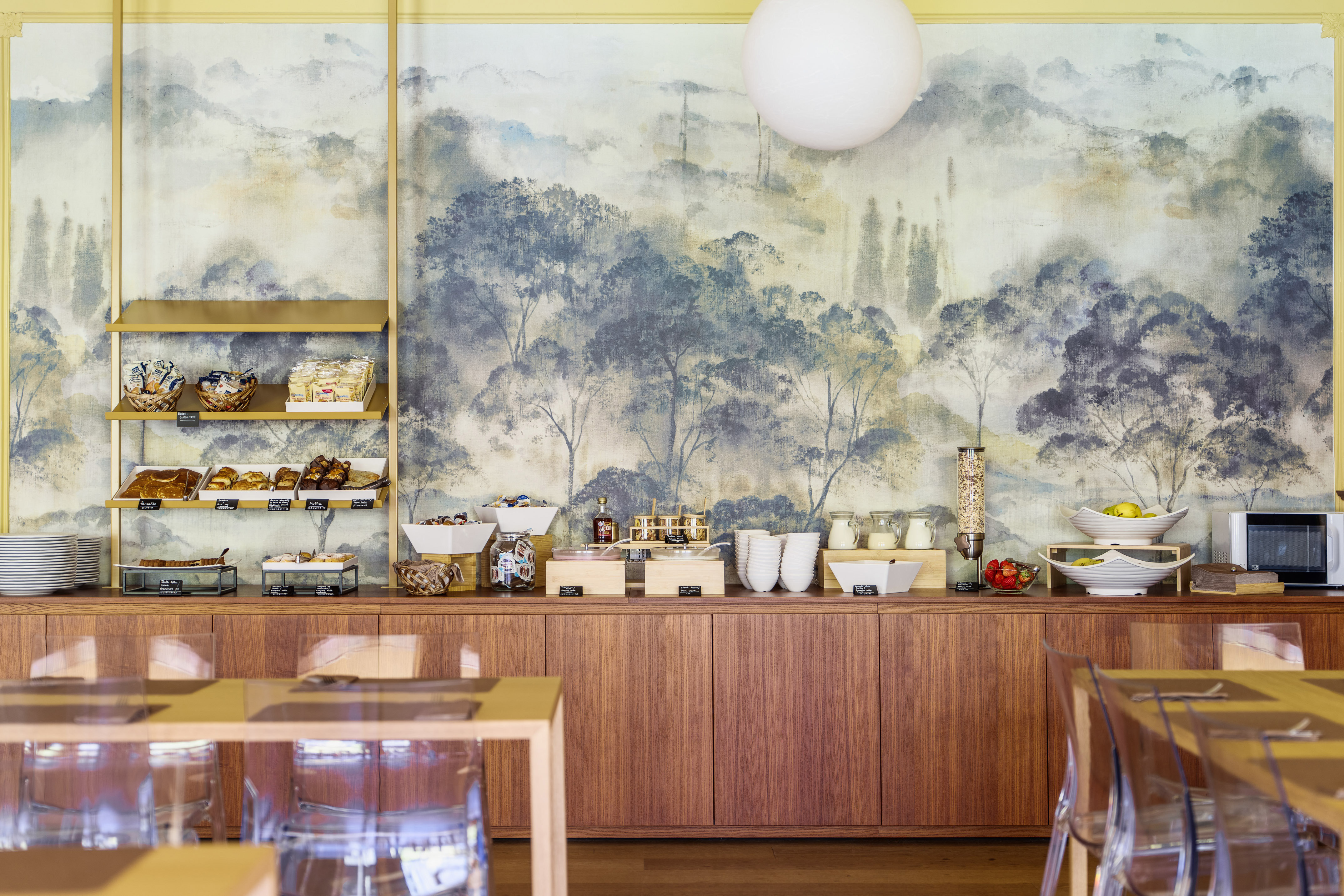 Bright hotel breakfast buffet with diverse foods and scenic mural.