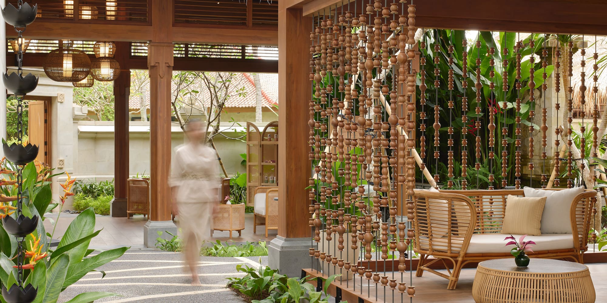 Tropical resort lounge with wood architecture, rattan furniture, and lush garden.