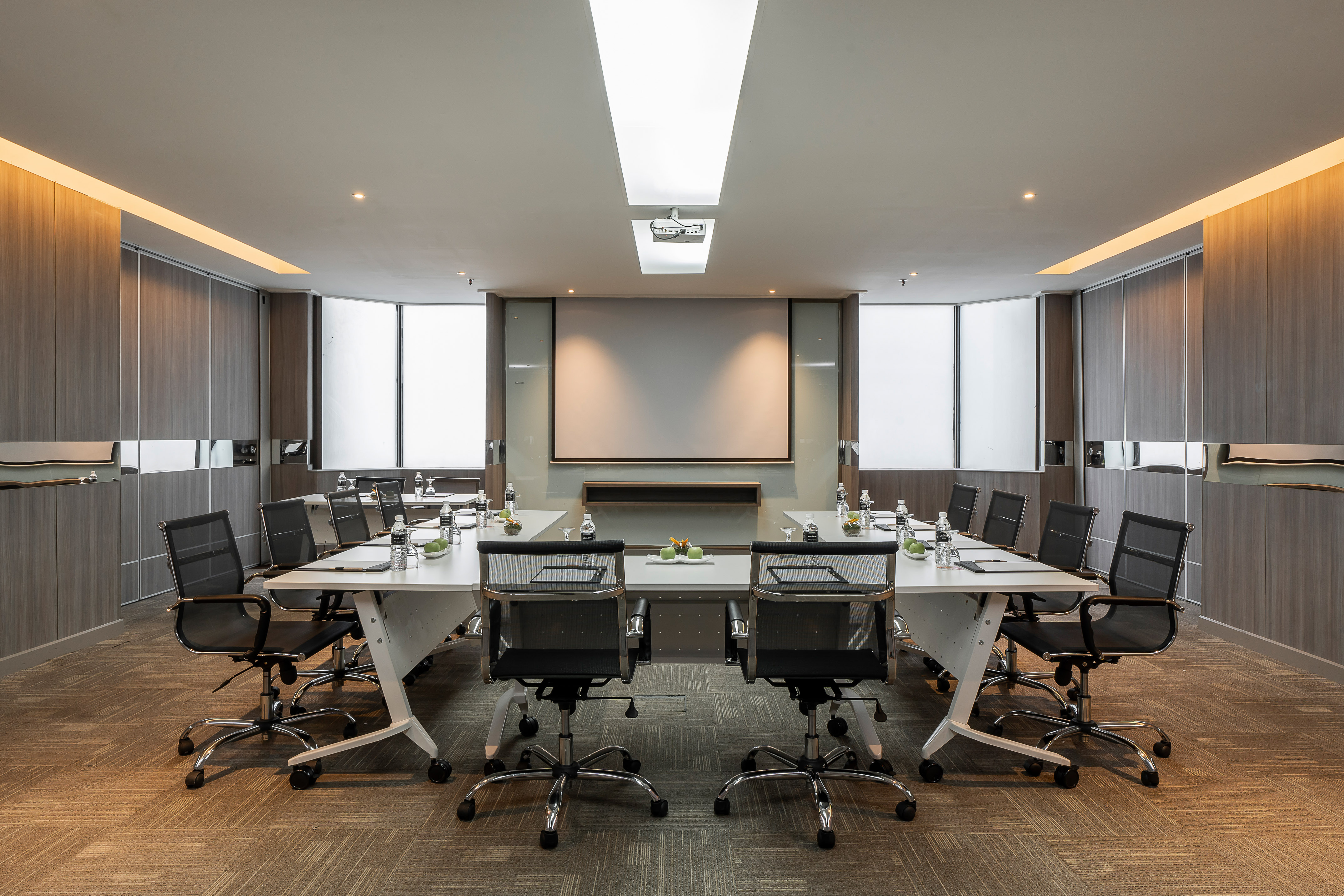 Empty modern meeting room with conference table and projector screen.