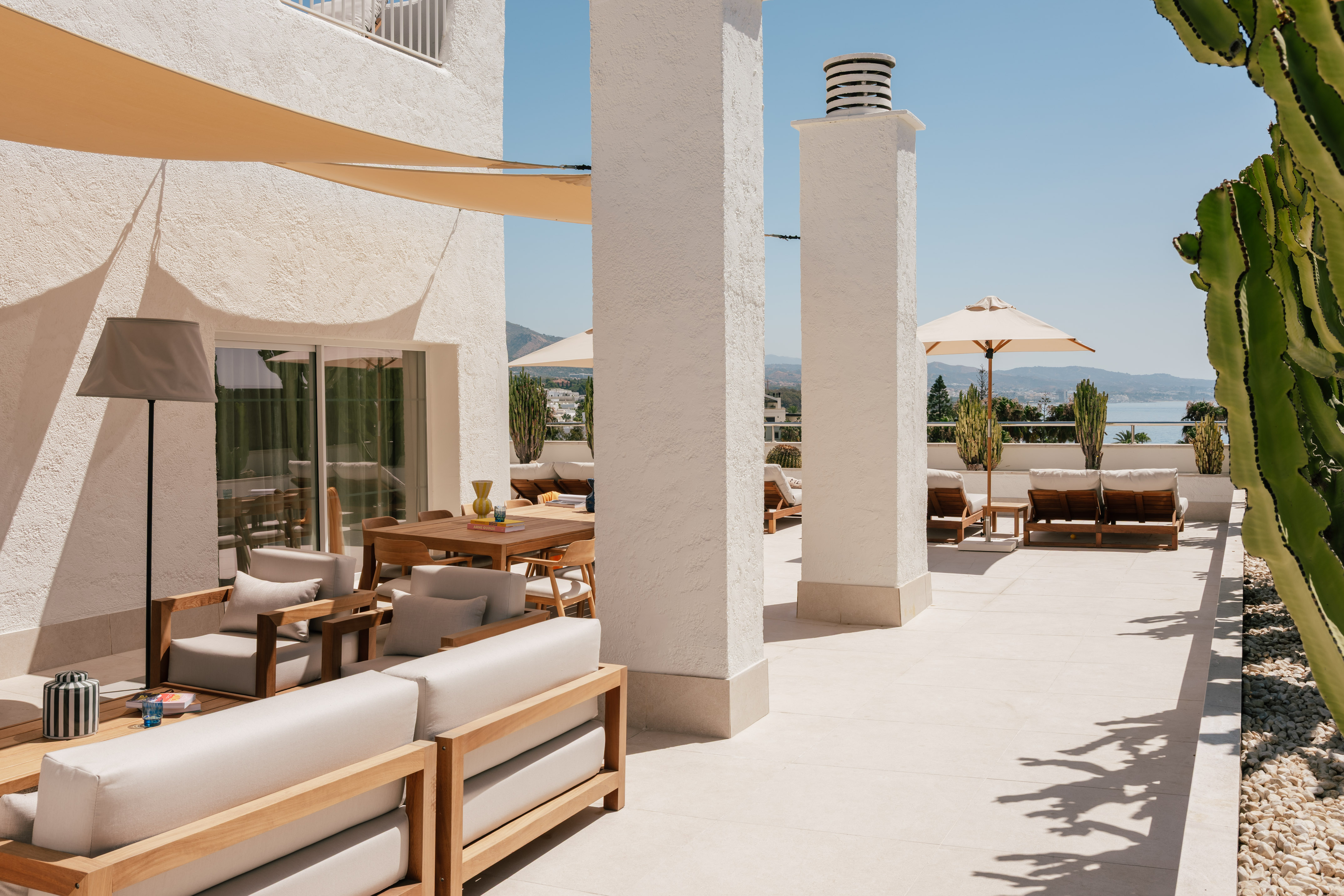 Modern outdoor terrace with lounge sofas, dining set, and sea view.