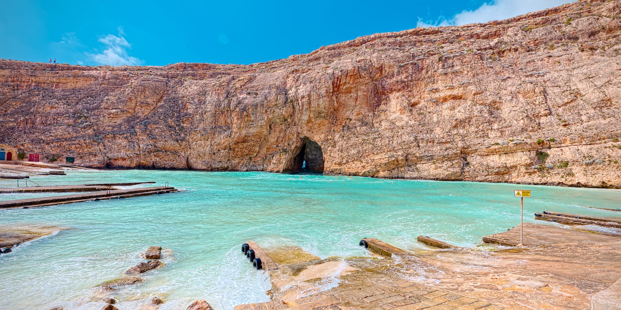 a rocky cliff with a cave in the water