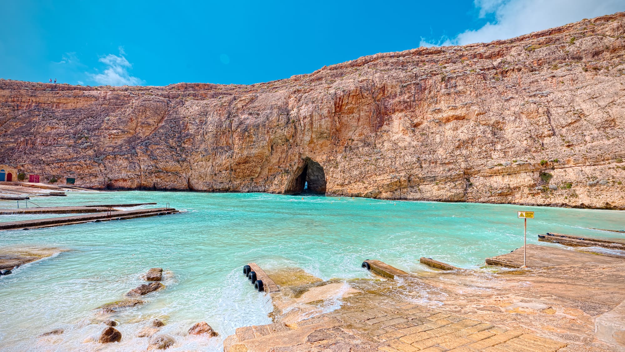 a rocky cliff with a cave in the water