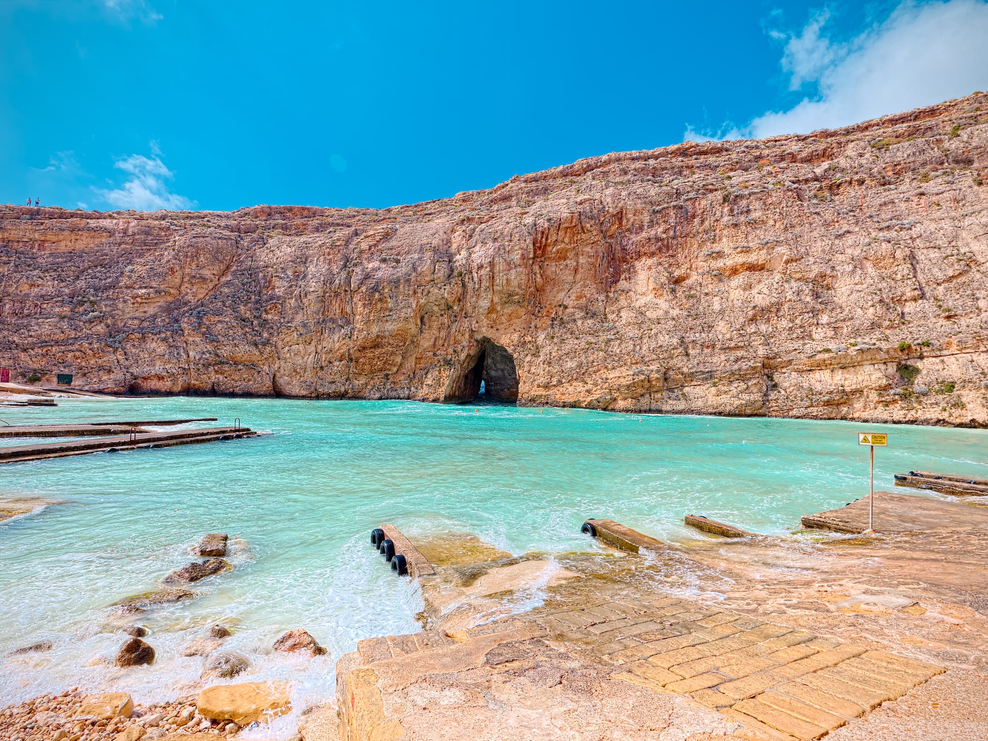 a rocky cliff with a cave in the water