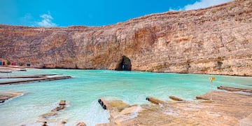 a rocky cliff with a cave in the water