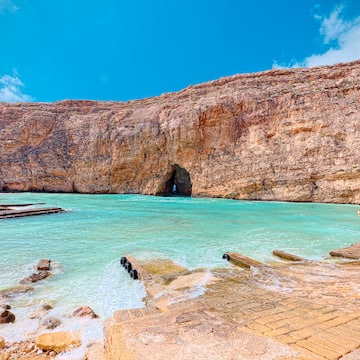 a rocky cliff with a cave in the water