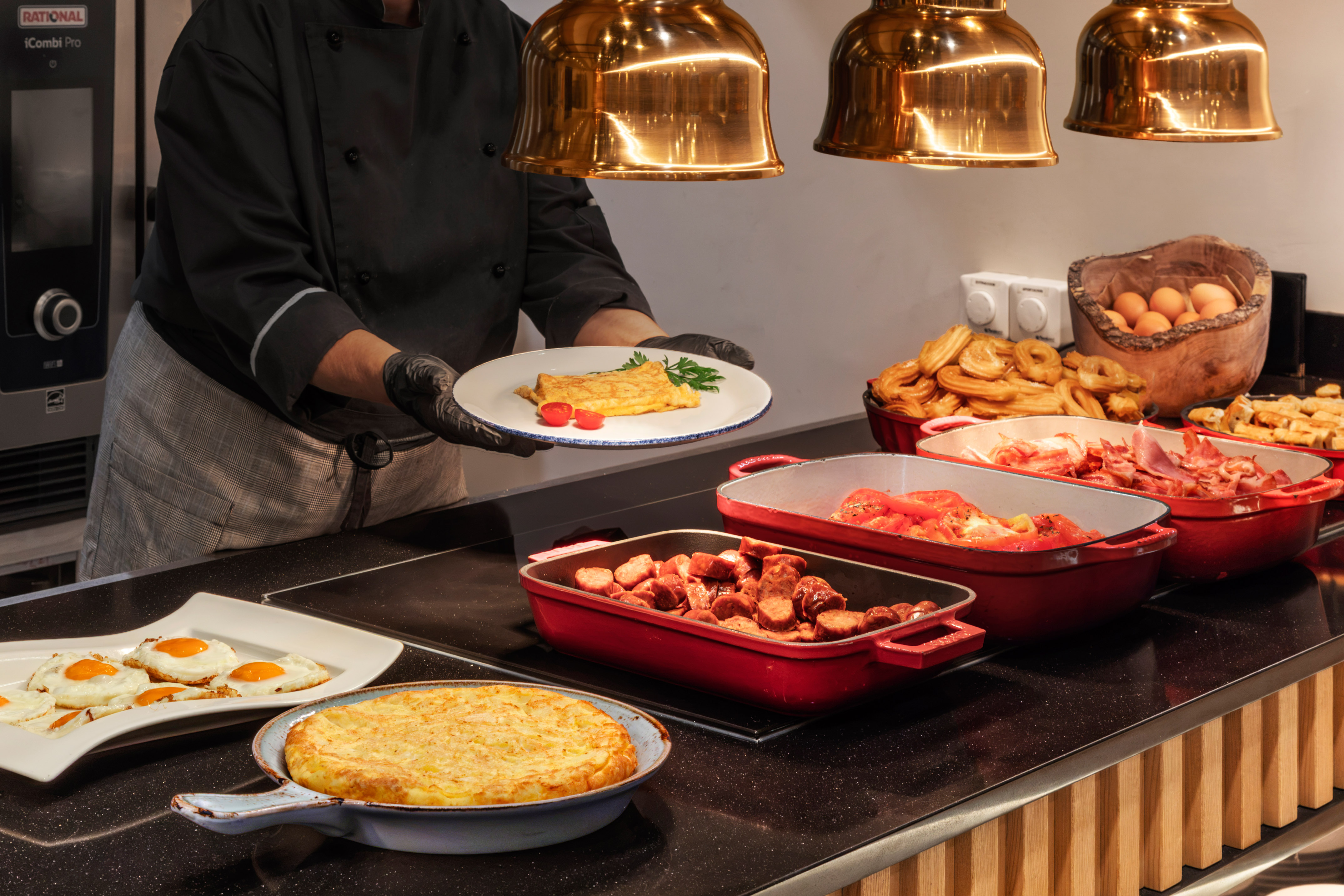 Chef sirviendo tortilla francesa en buffet de desayuno caliente.