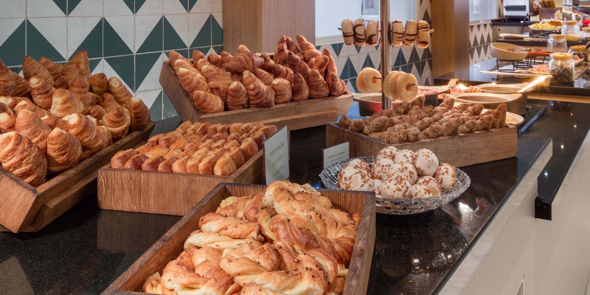 Hotel breakfast buffet with golden croissants, assorted pastries, and donuts.