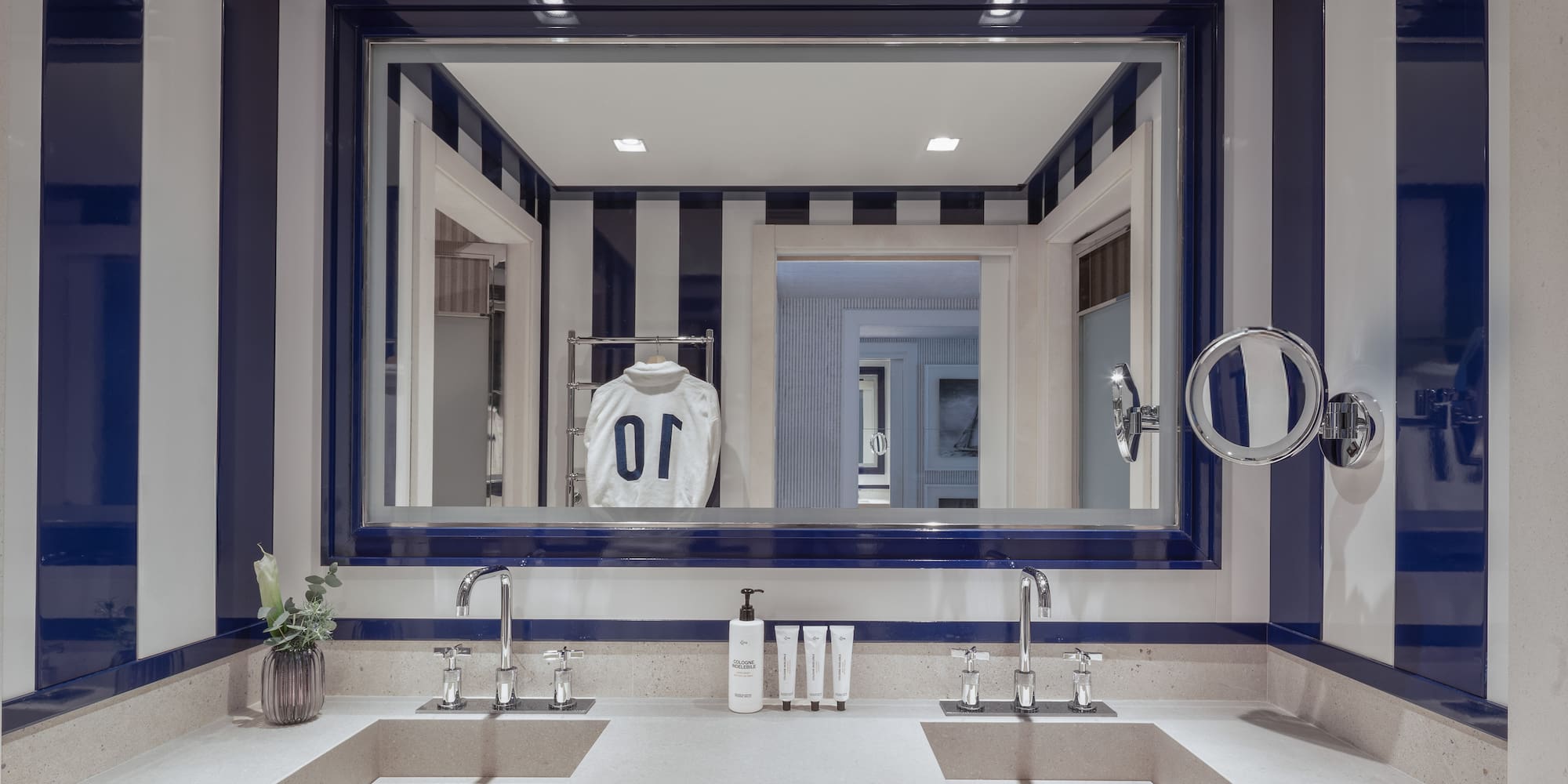a bathroom with a mirror and a white and blue striped wall
