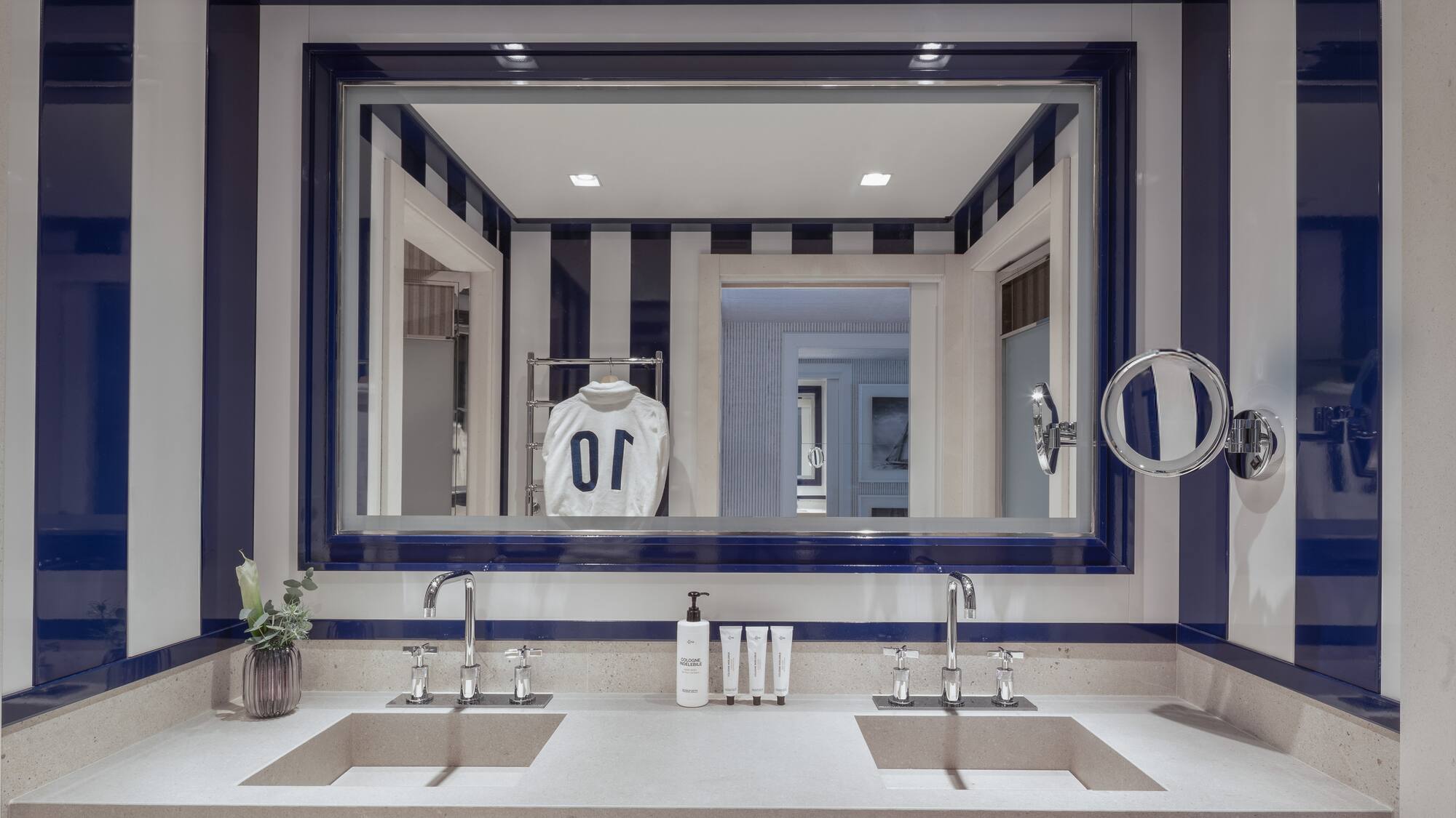 a bathroom with a mirror and a white and blue striped wall