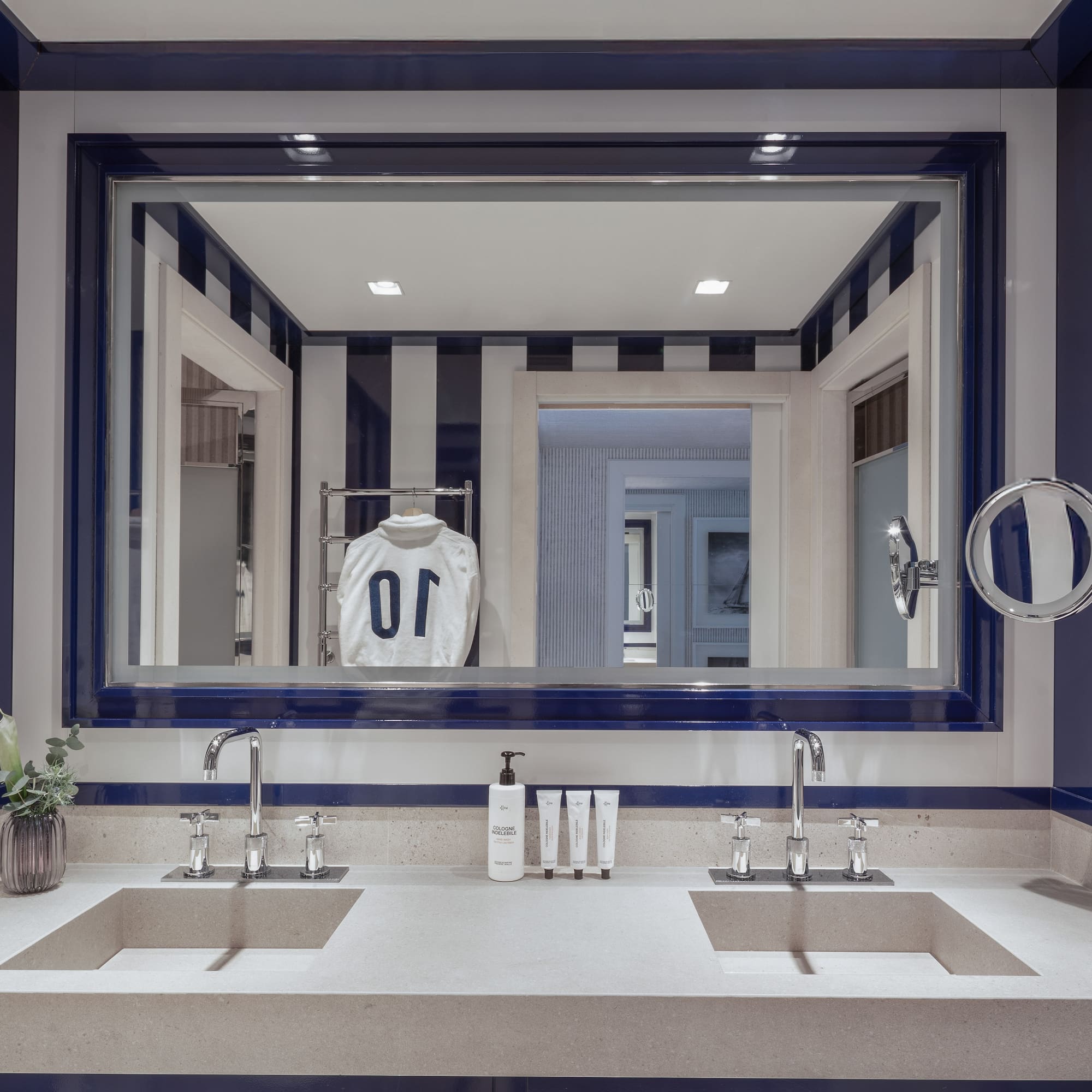 a bathroom with a mirror and a white and blue striped wall