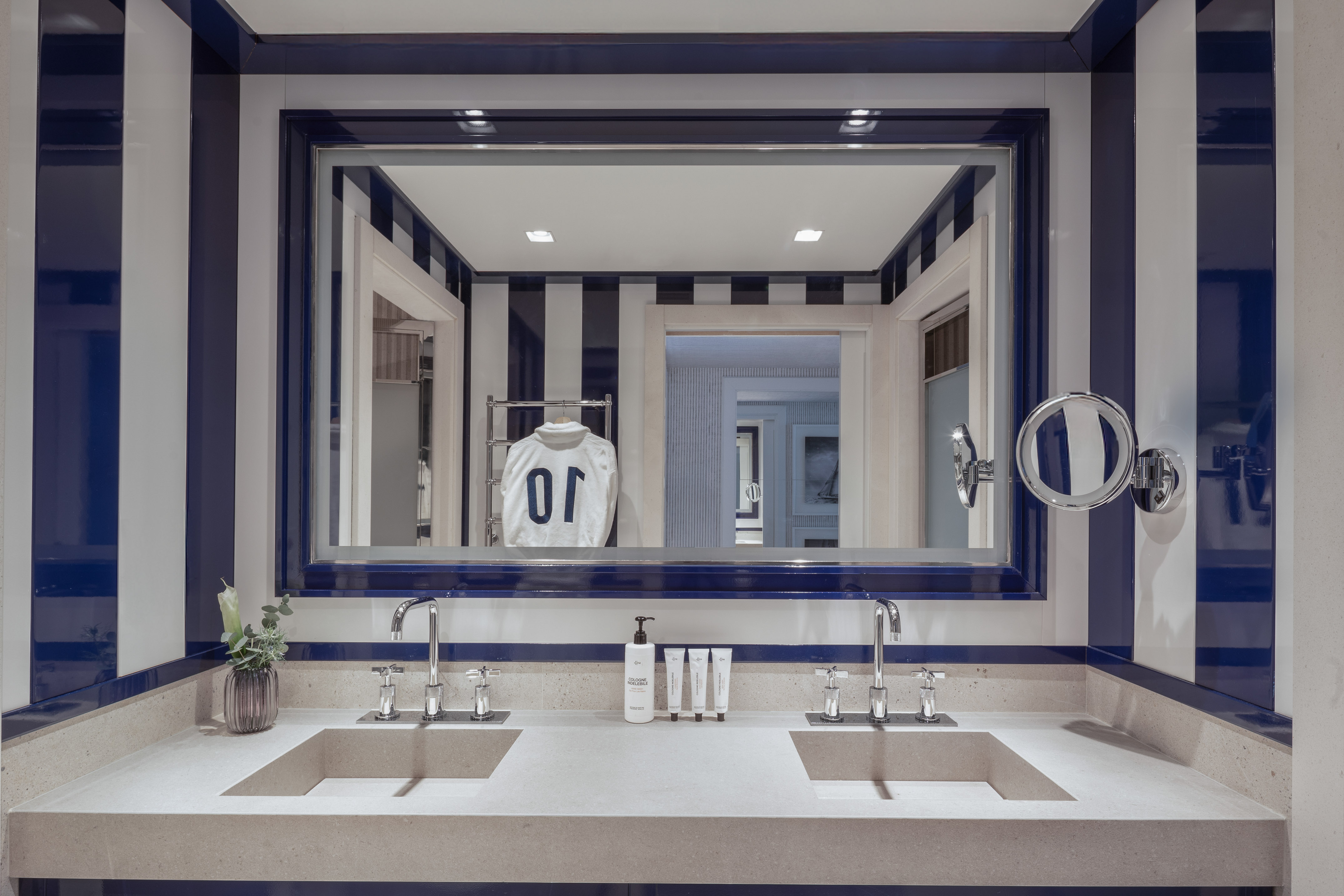 Blue and white striped bathroom with double vanity, stone sinks, and mirror.