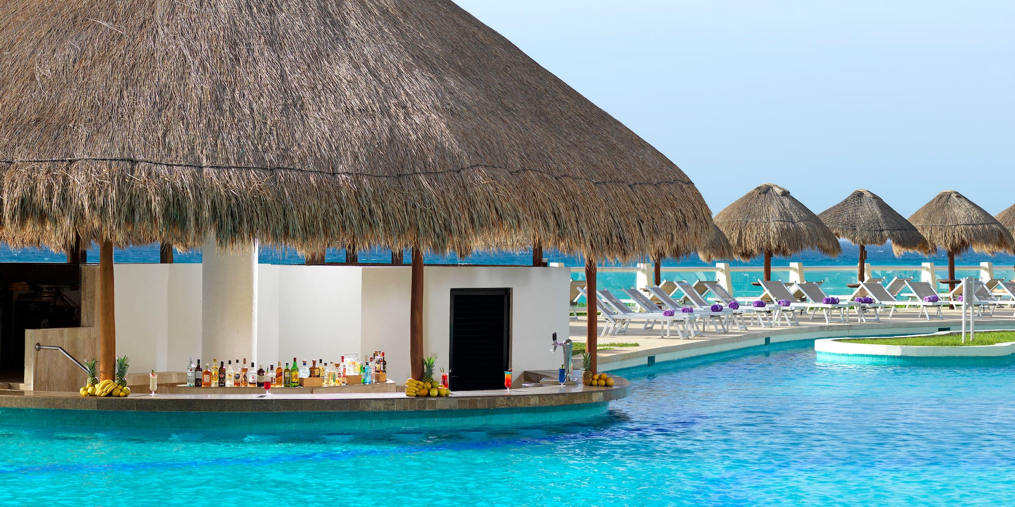 a pool with a thatched roof and a bar