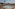 a pool with a fountain and umbrellas and a beach