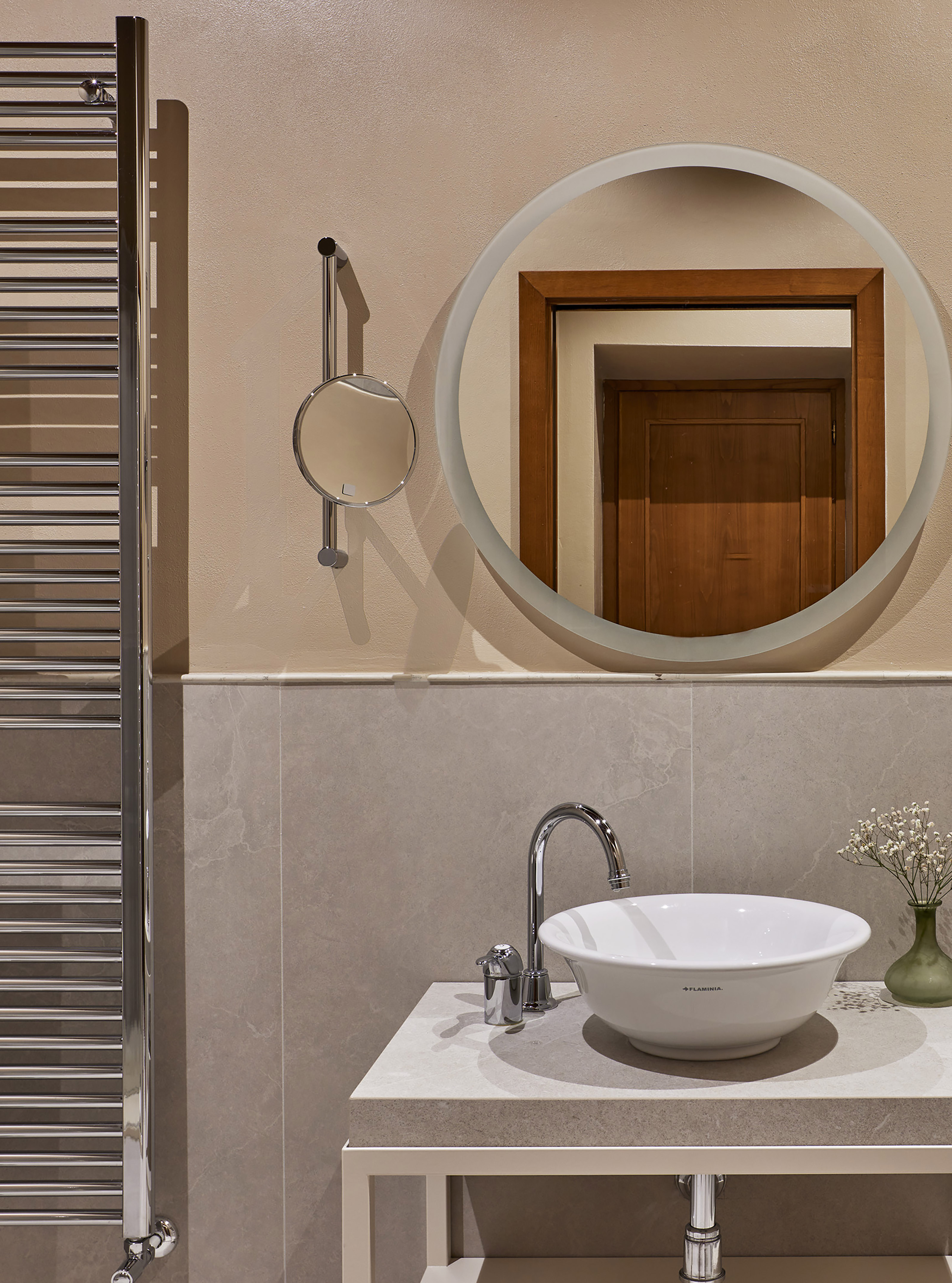 Modern bathroom: vessel sink, chrome faucet, illuminated mirror, heated towel rail.