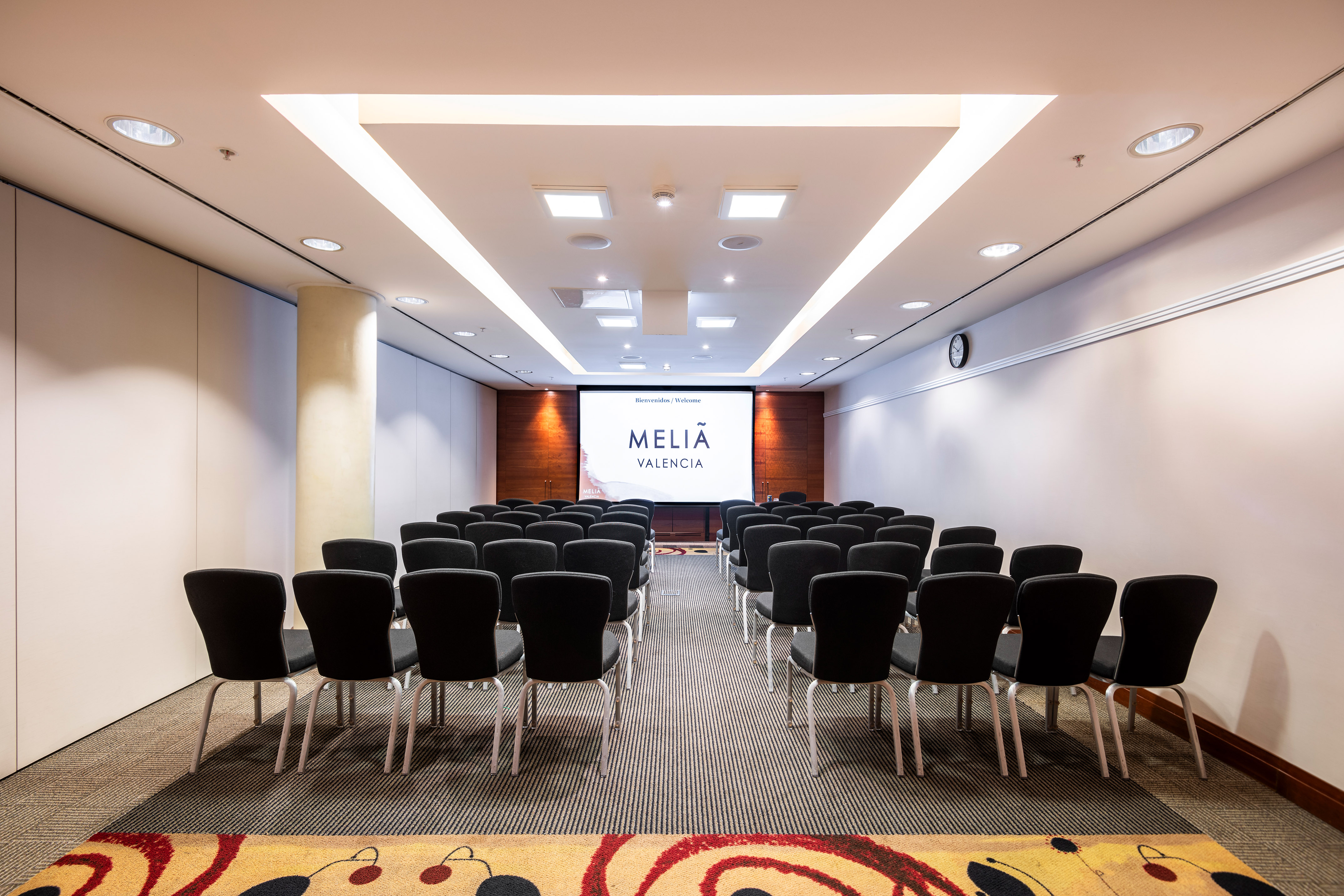 Modern Melia Valencia meeting room with screen and theater seating.