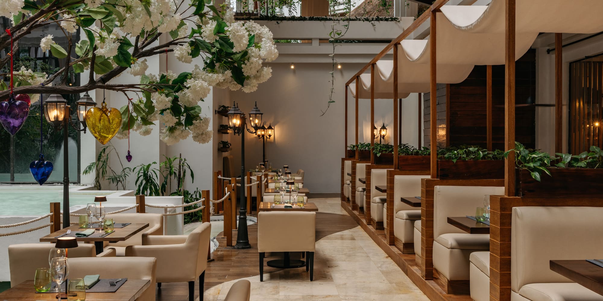 Elegant restaurant interior with white flowers, lanterns, and modern beige seating.
