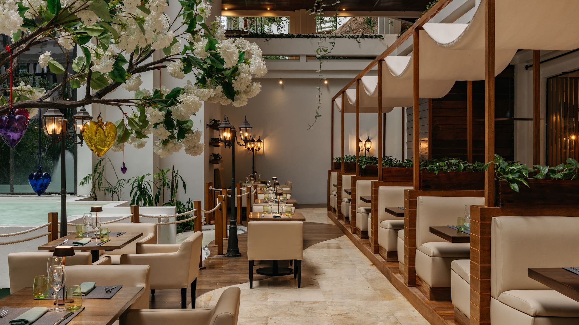Elegant restaurant interior with white flowers, lanterns, and modern beige seating.