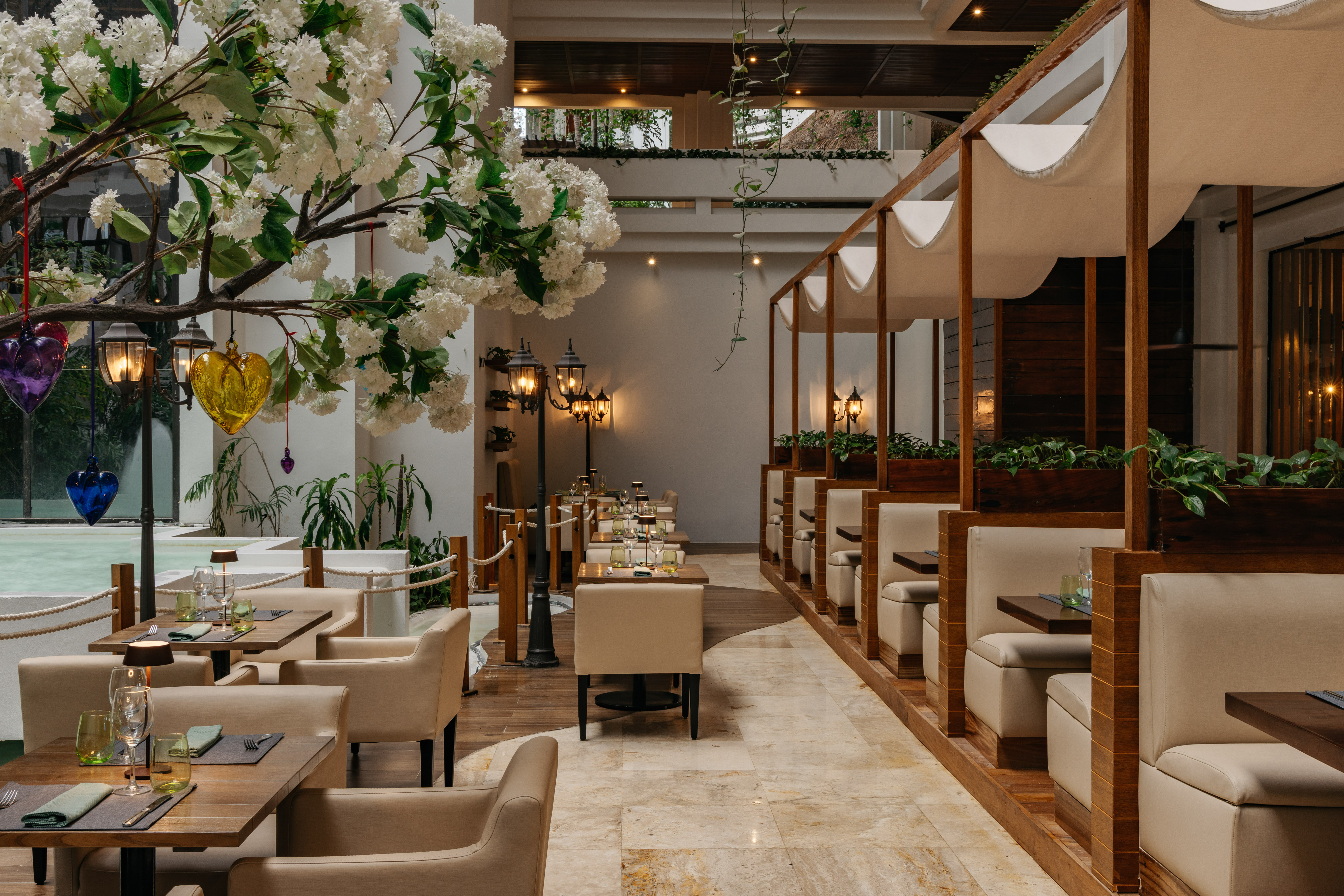 Elegant restaurant interior with white flowers, lanterns, and modern beige seating.