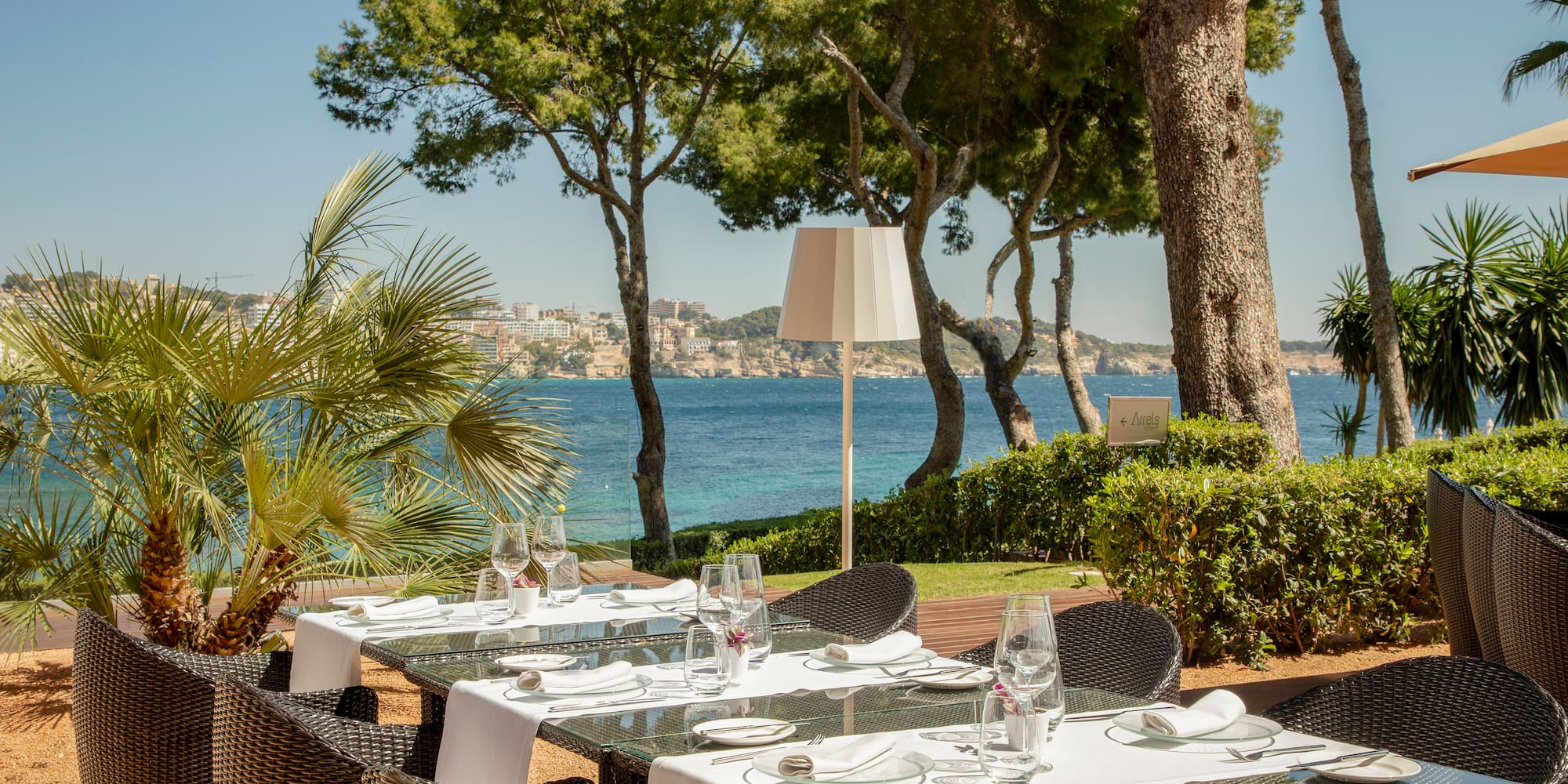 a table set up for a meal outside with trees and water in the background