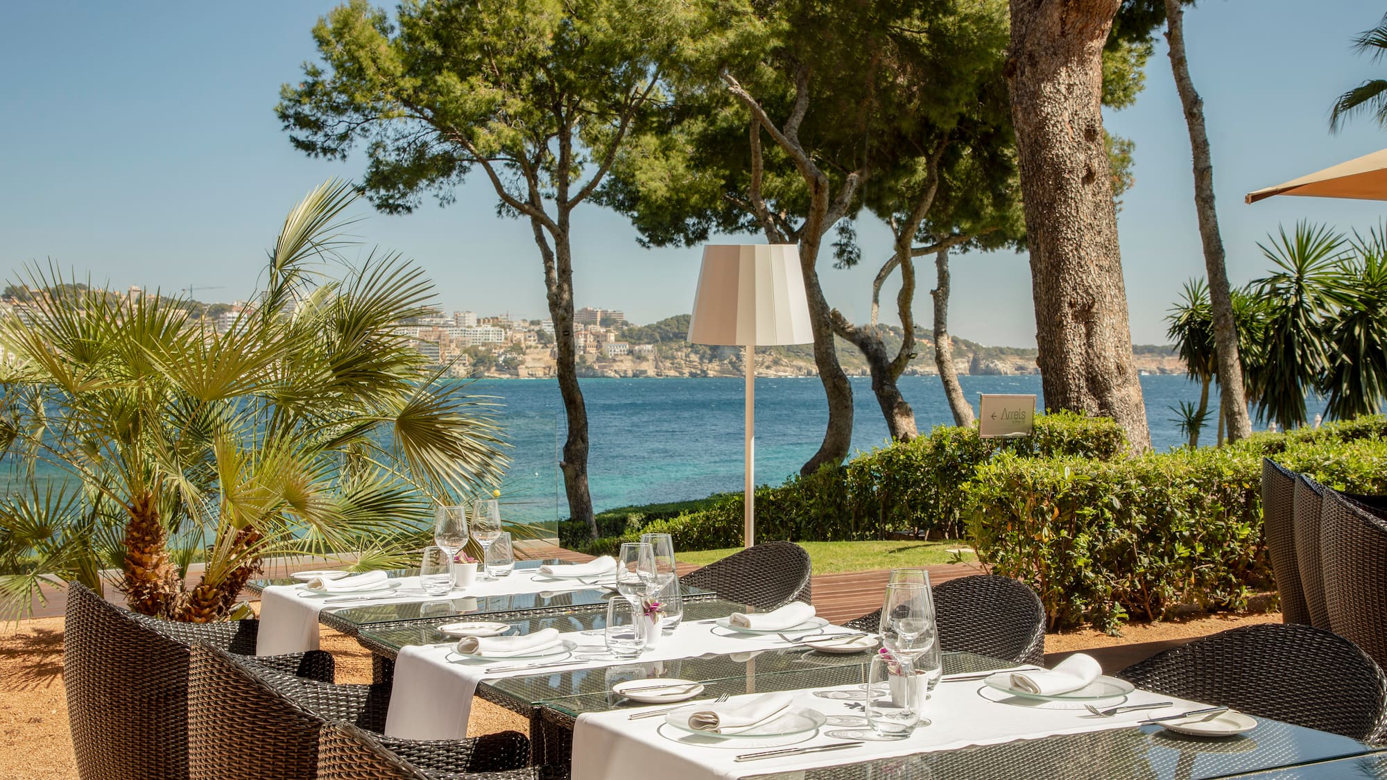 a table set up for a meal outside with trees and water in the background