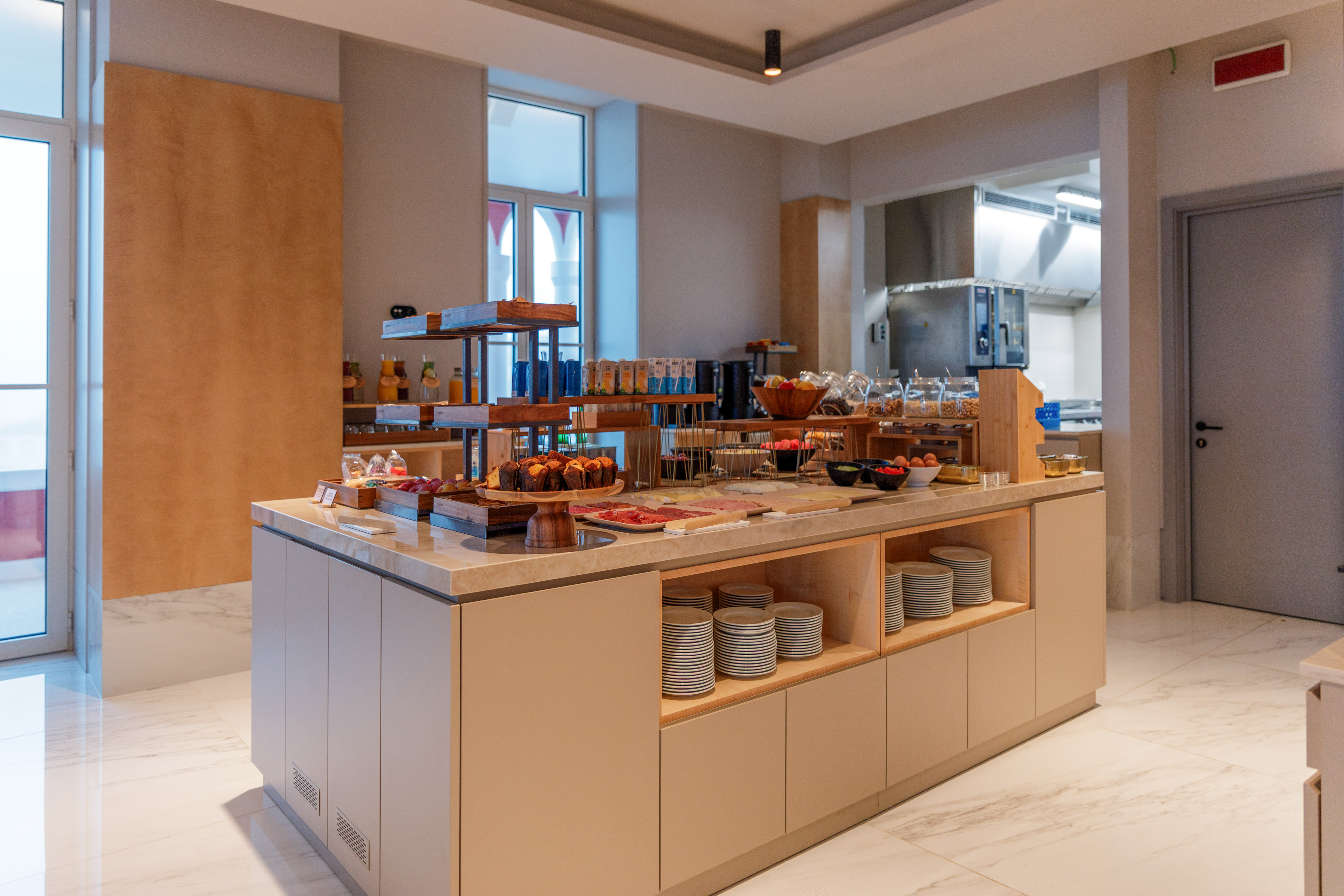 Modern hotel breakfast buffet with pastries, fruits, juices, and cold cuts.