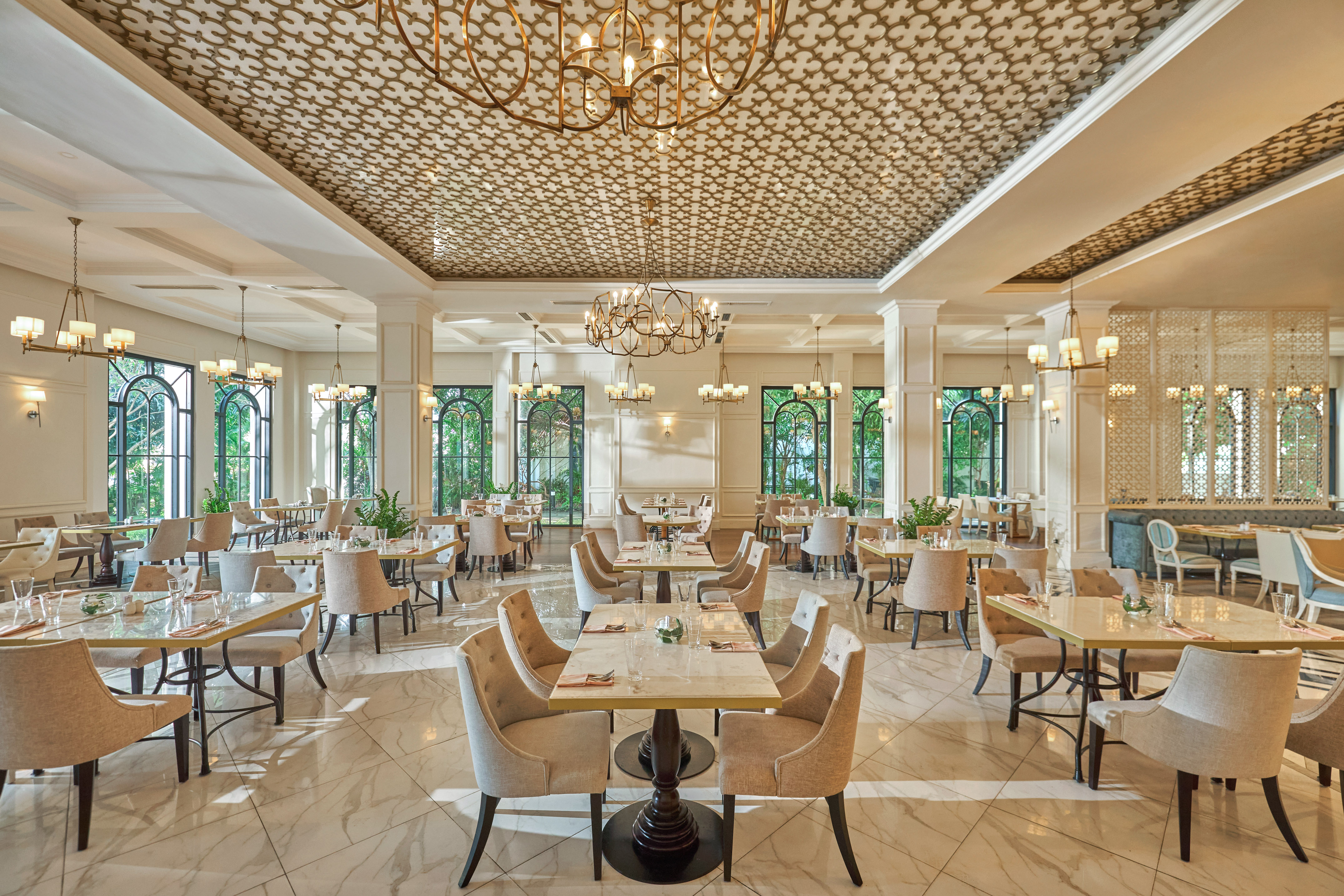 Elegant restaurant dining room with ornate ceiling, chandeliers, and arched windows.