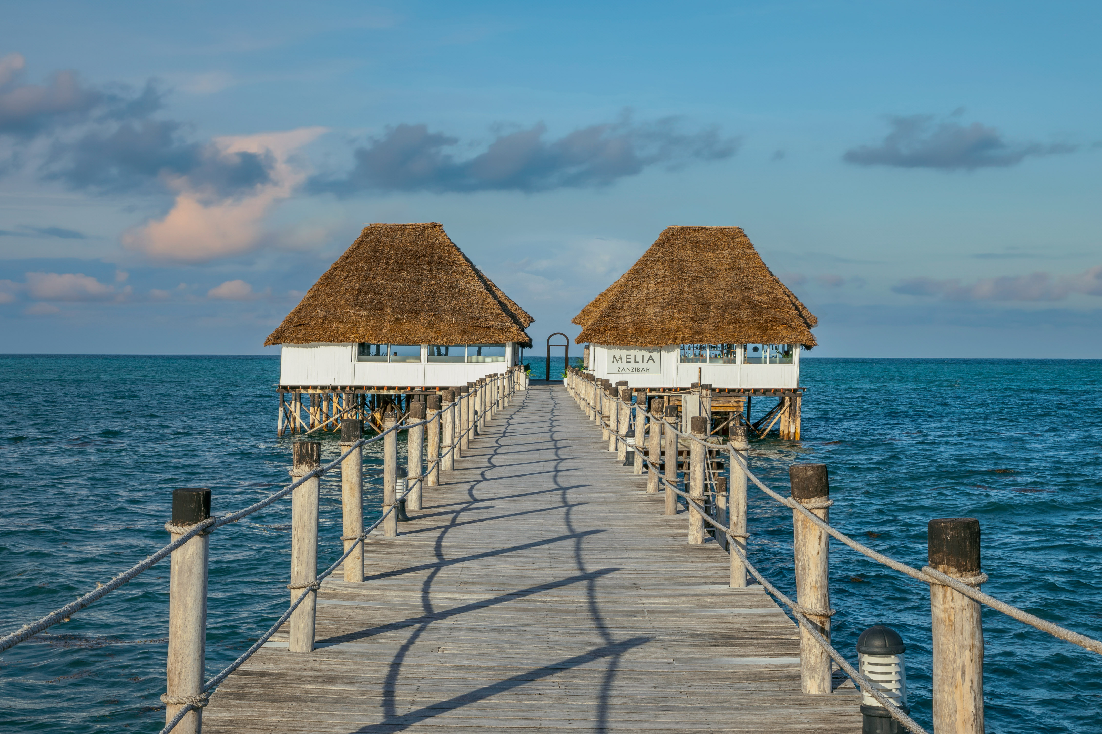 Melia Zanzibar resort pier with overwater thatched roof pavilions.