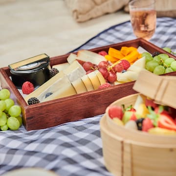 a tray of fruit and cheese on a blanket