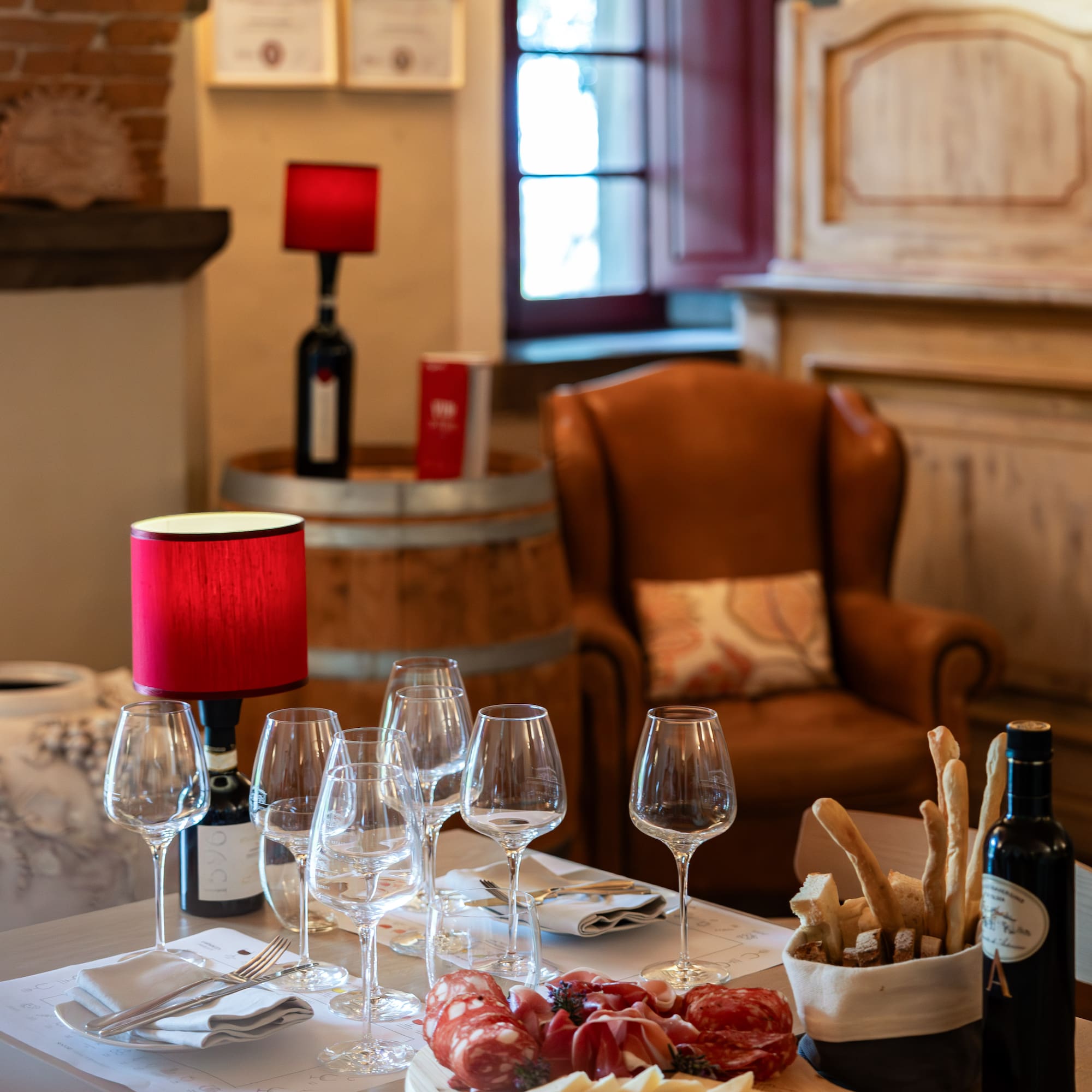 Table set for wine tasting with charcuterie, cheese, wine glasses, and bread.