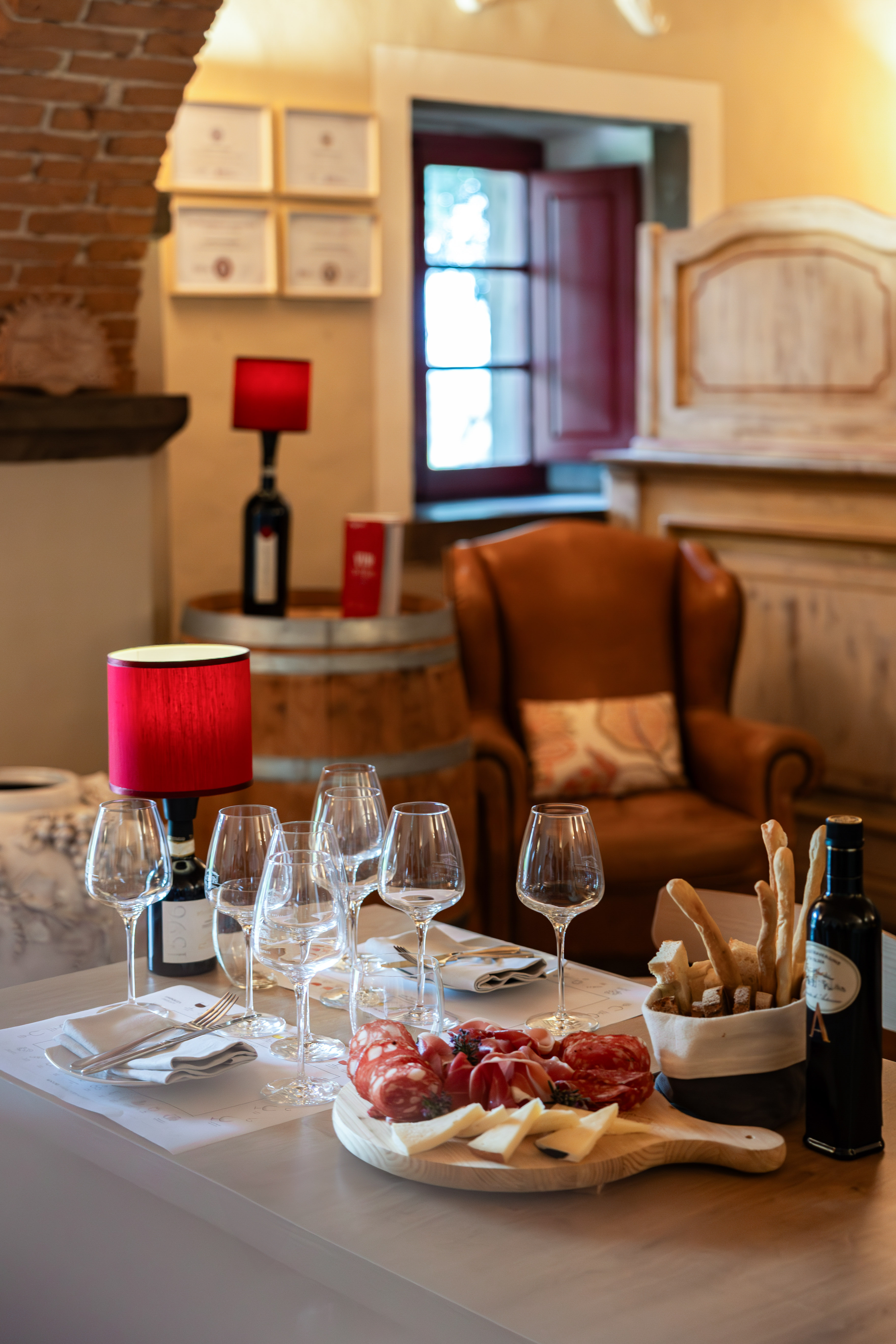 Table set for wine tasting with charcuterie, cheese, wine glasses, and bread.