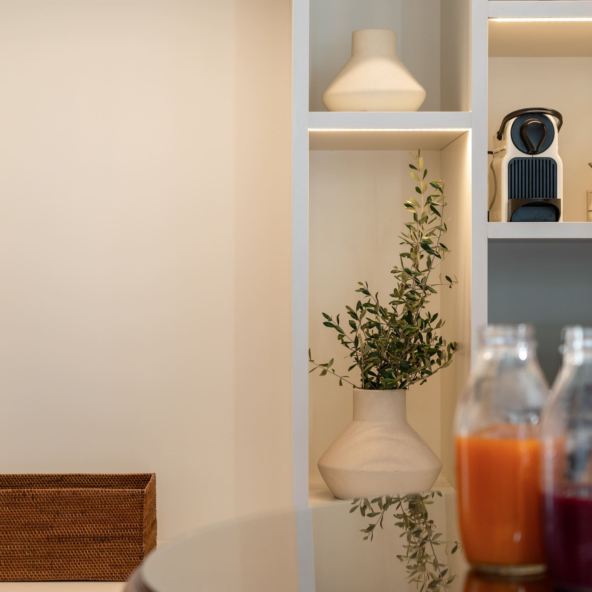 a shelf with a plant and bottles of juice