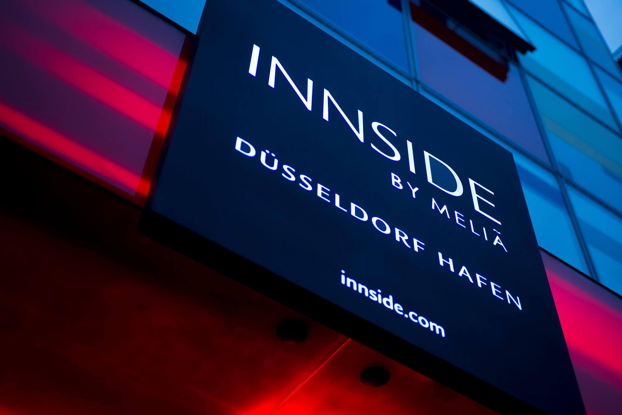 Illuminated INNSIDE by Melia Düsseldorf Hafen hotel sign with red glow.