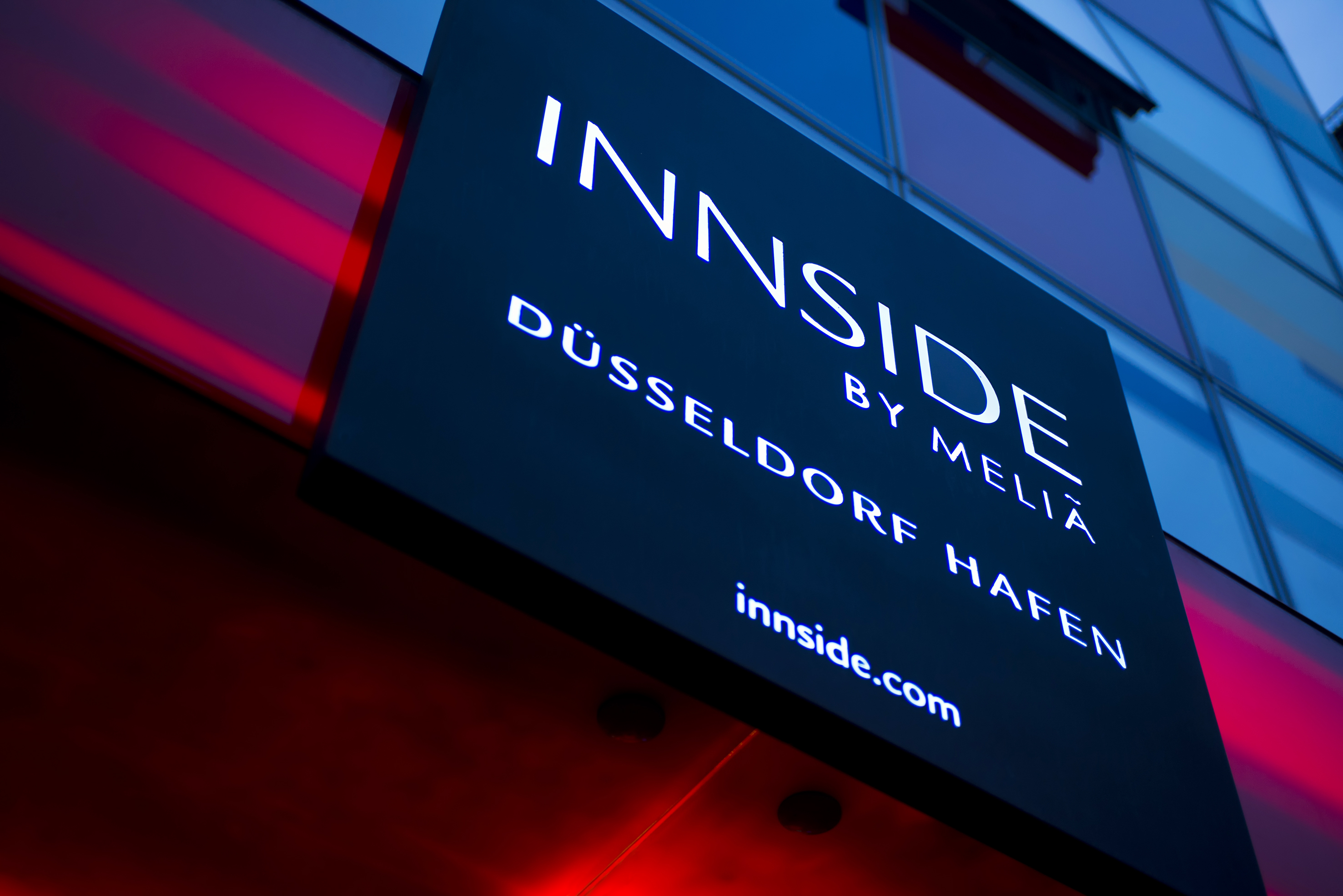 Illuminated INNSIDE by Melia Düsseldorf Hafen hotel sign with red glow.
