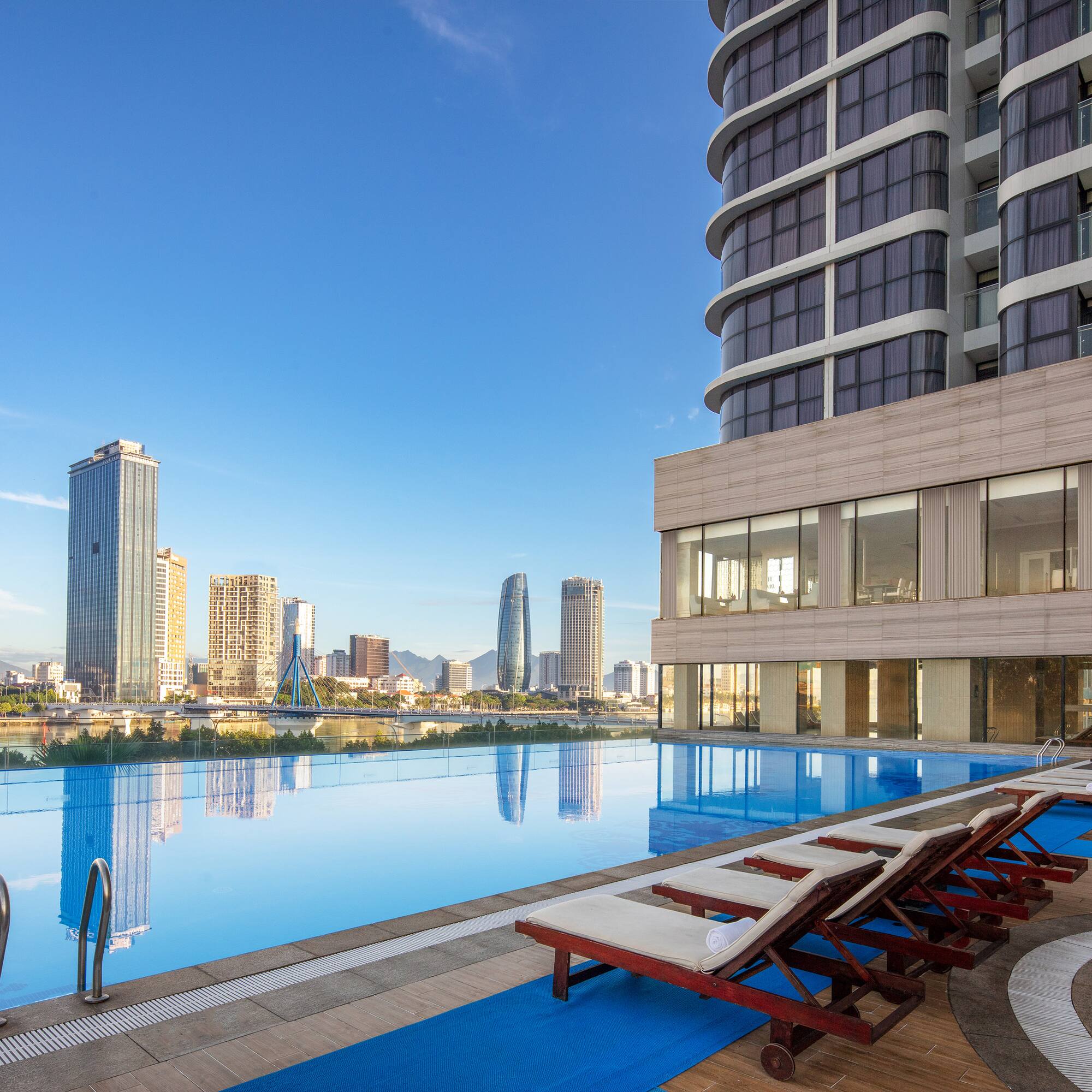 a pool with chairs and a building in the background