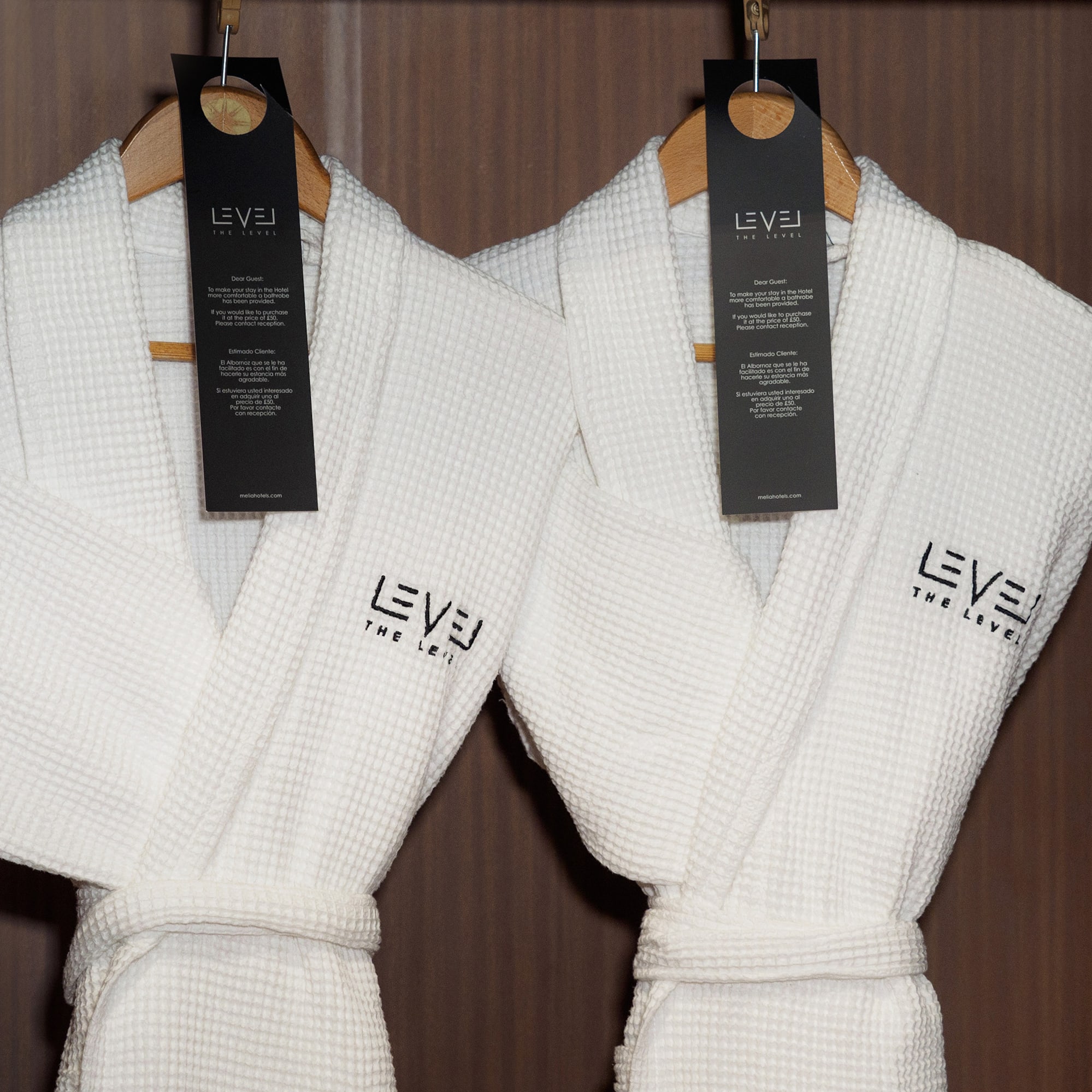 Two white waffle luxury hotel bathrobes by "LEVEL THE LEVEL" in wardrobe.