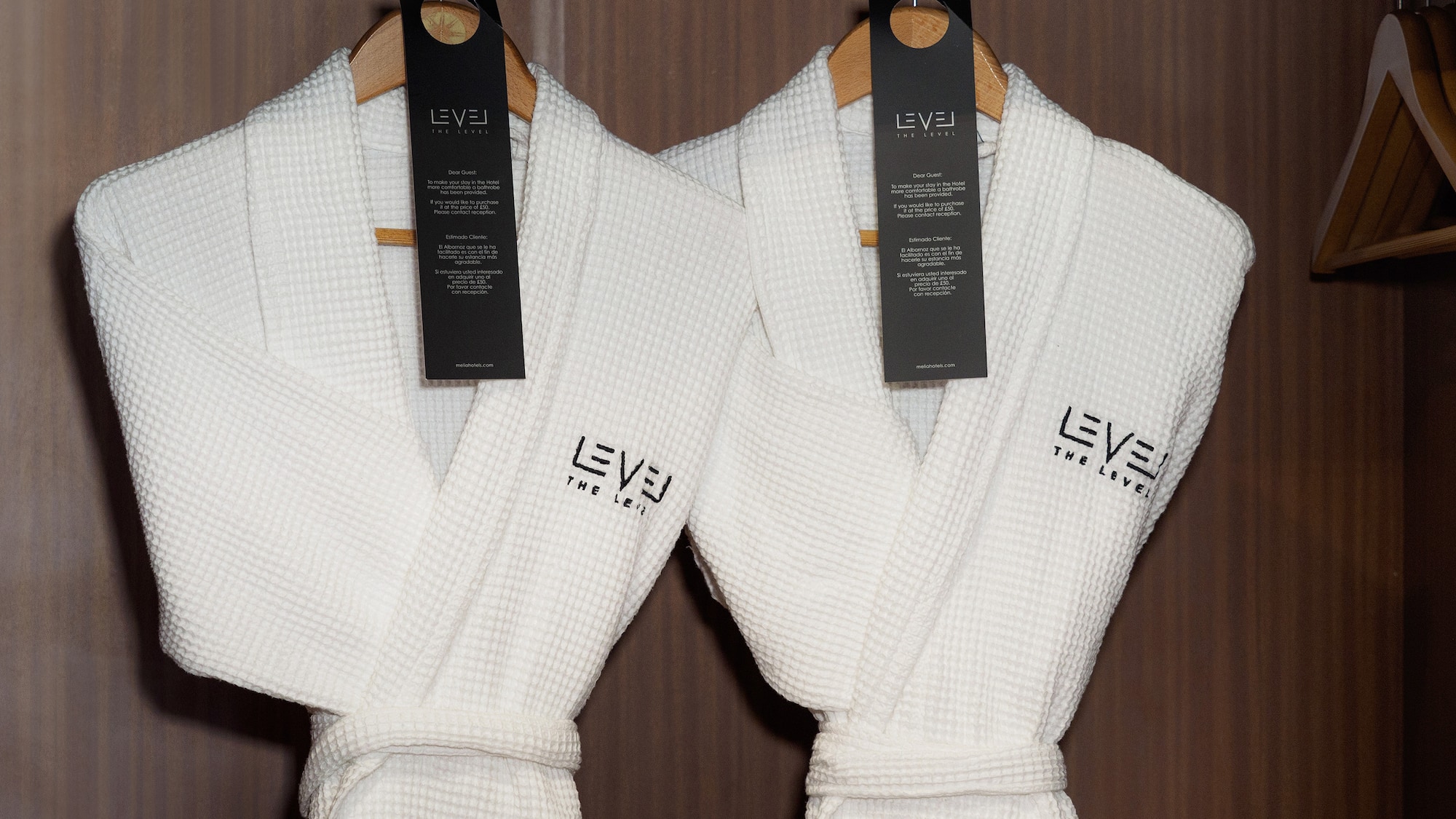 Two white waffle luxury hotel bathrobes by "LEVEL THE LEVEL" in wardrobe.