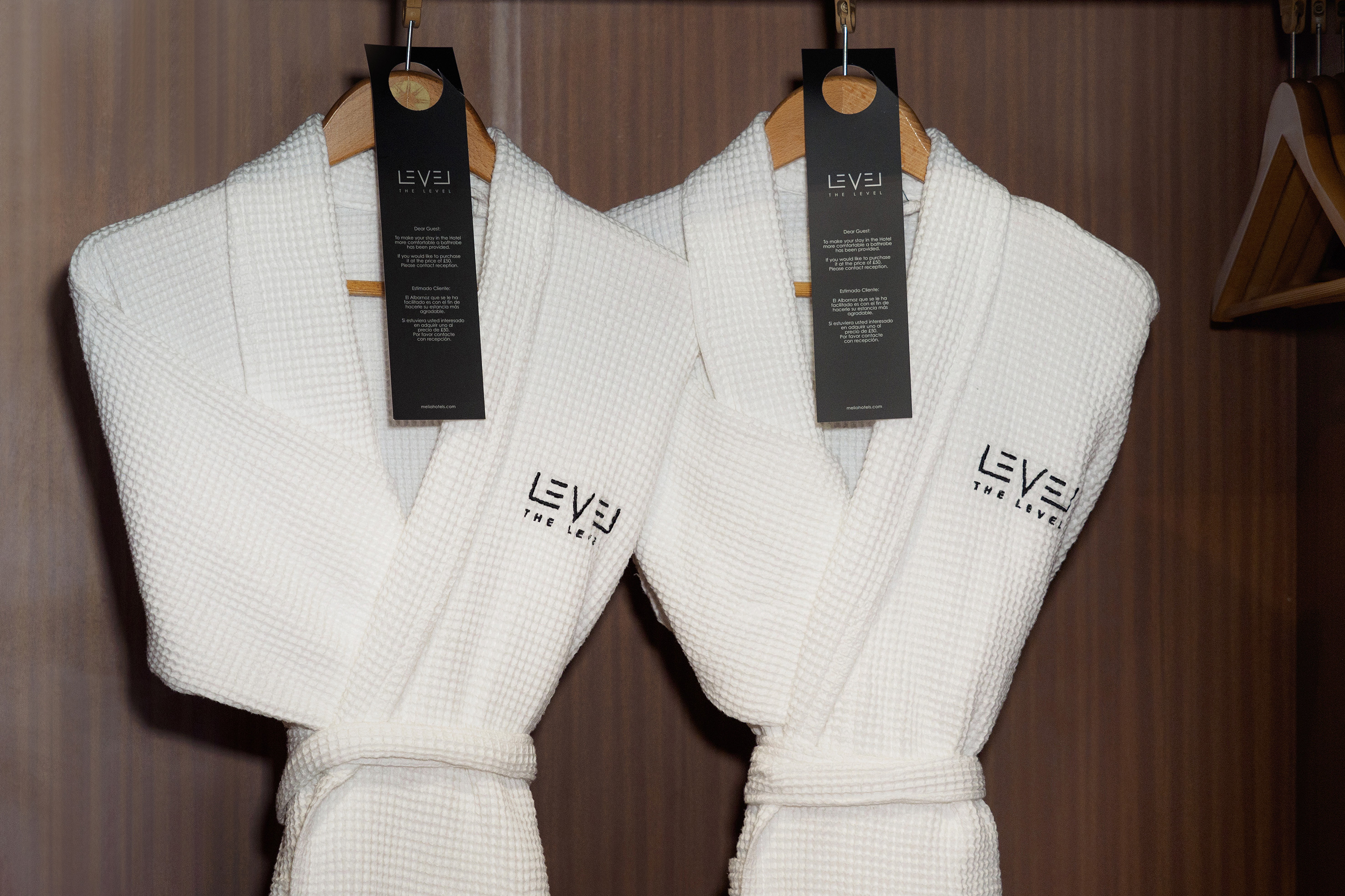 Two white waffle luxury hotel bathrobes by "LEVEL THE LEVEL" in wardrobe.