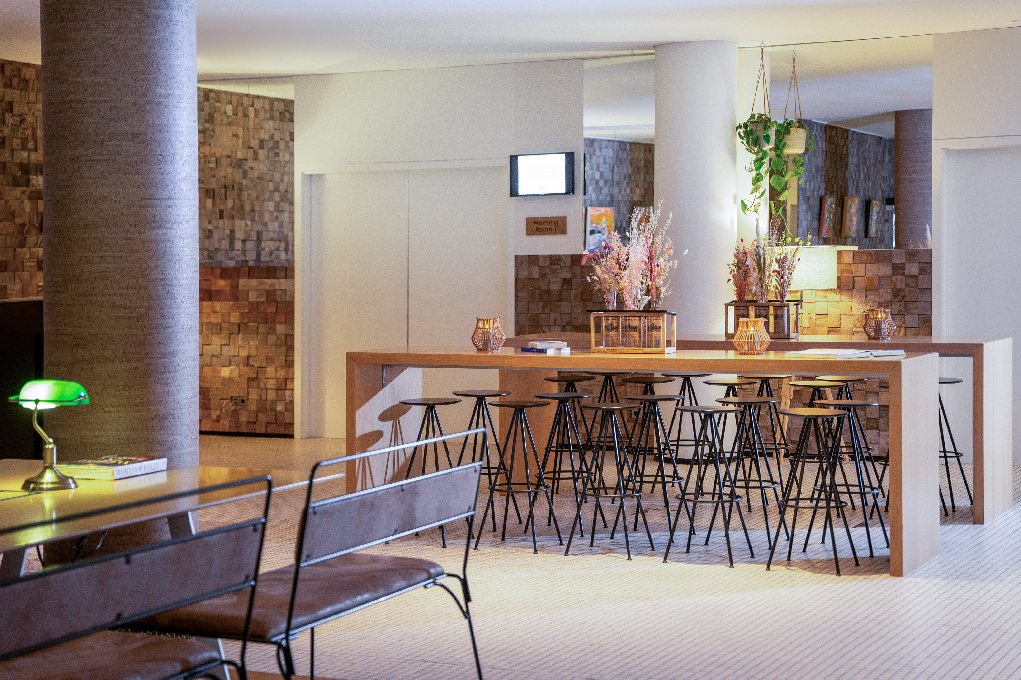 Stylish hotel co-working space with communal table, bar stools, and wood walls.