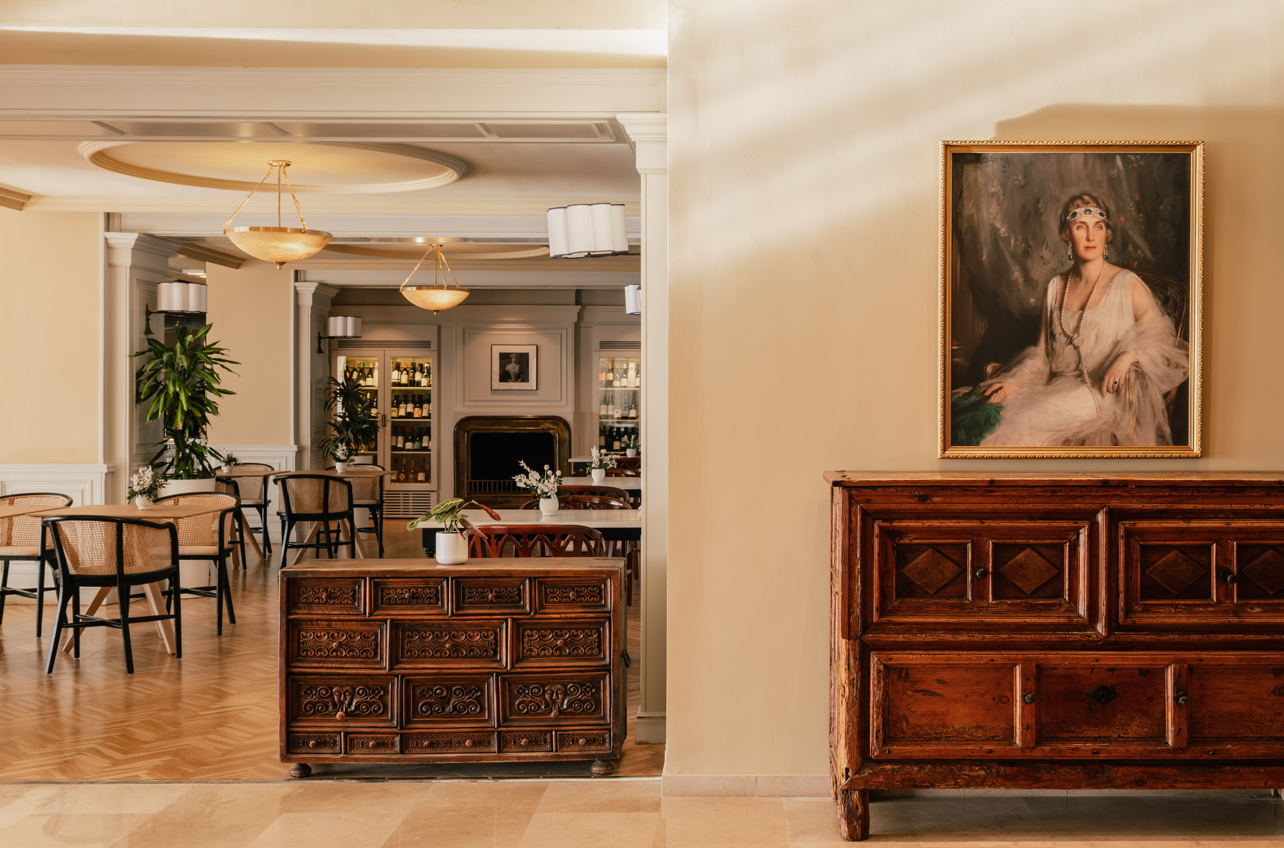 Elegant restaurant dining area with wine bar and classic portrait painting.