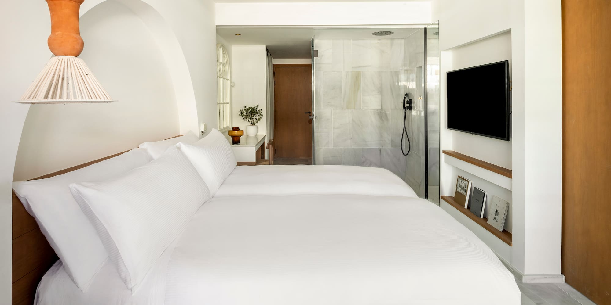 a bed with white sheets and a tv in a room