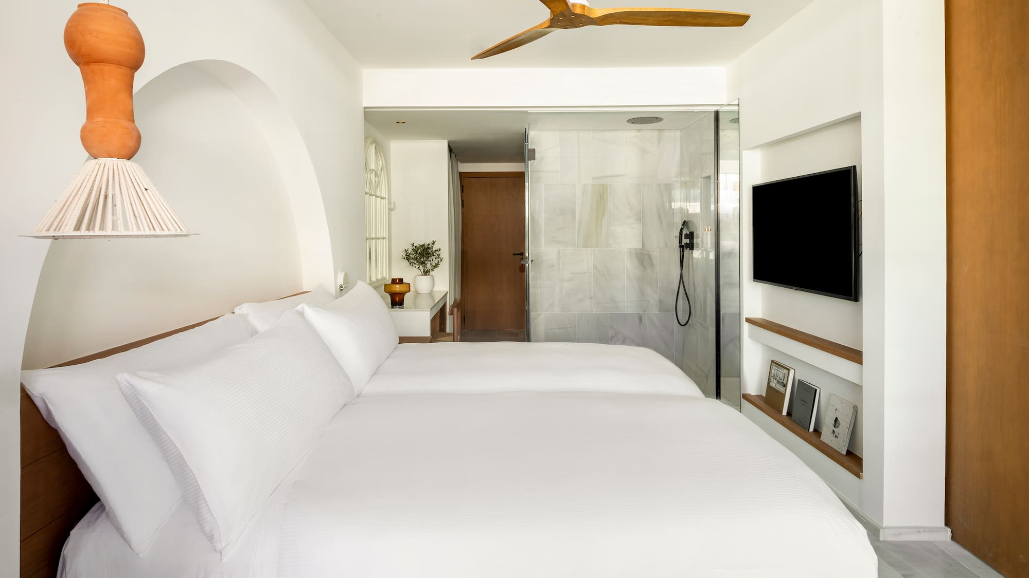 a bed with white sheets and a tv in a room