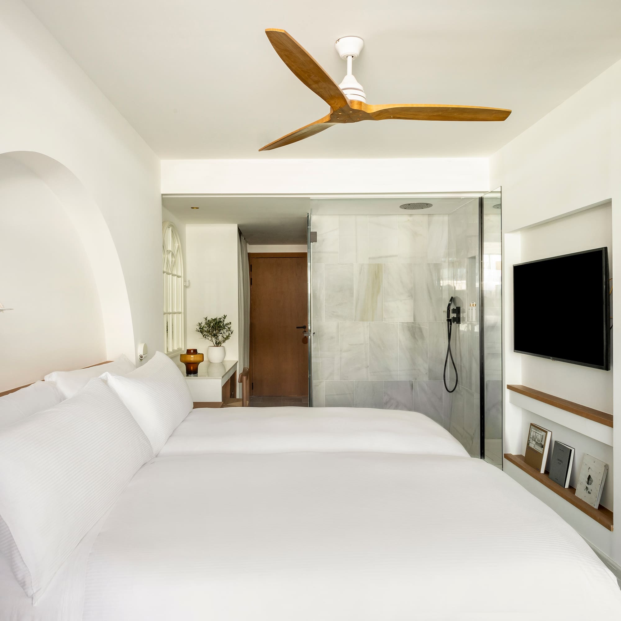 a bed with white sheets and a tv in a room