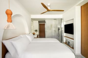 a bed with white sheets and a tv in a room