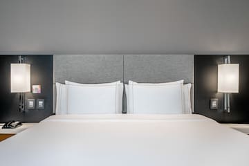 a bed with white sheets and a grey headboard