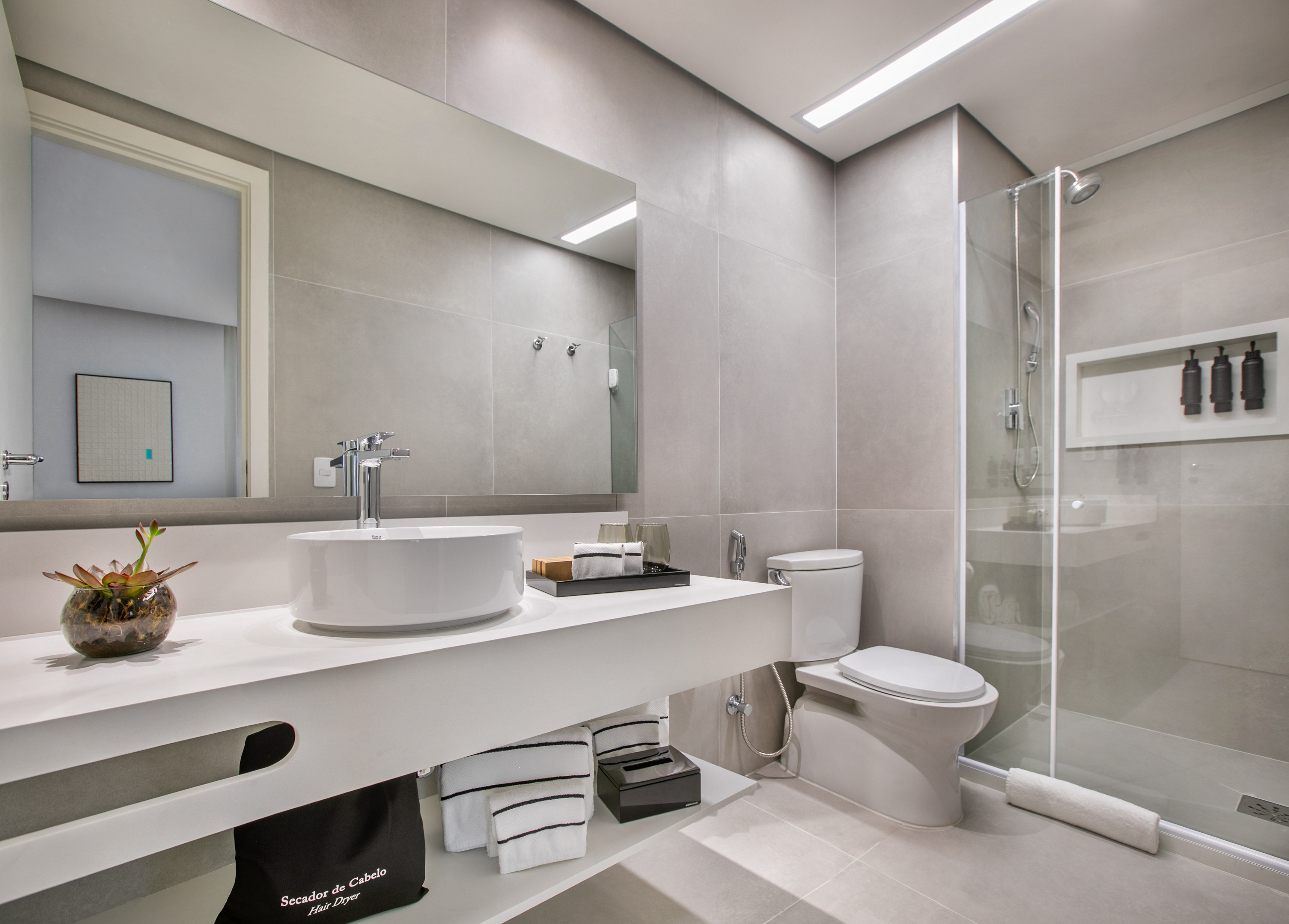 Modern gray bathroom with white vanity, vessel sink, and glass shower.