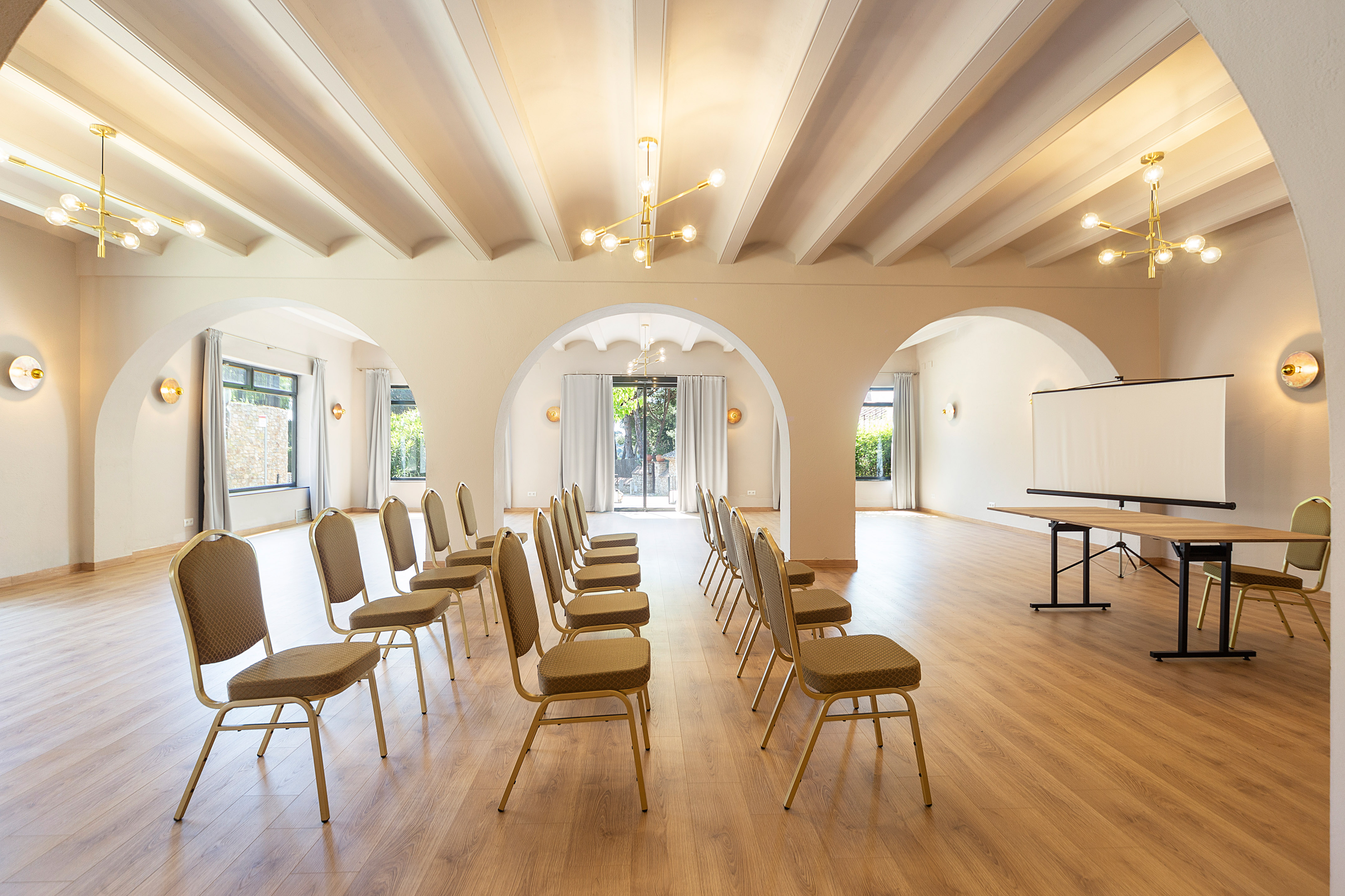 Modern conference room setup with chairs, screen, arched ceiling, and lighting.